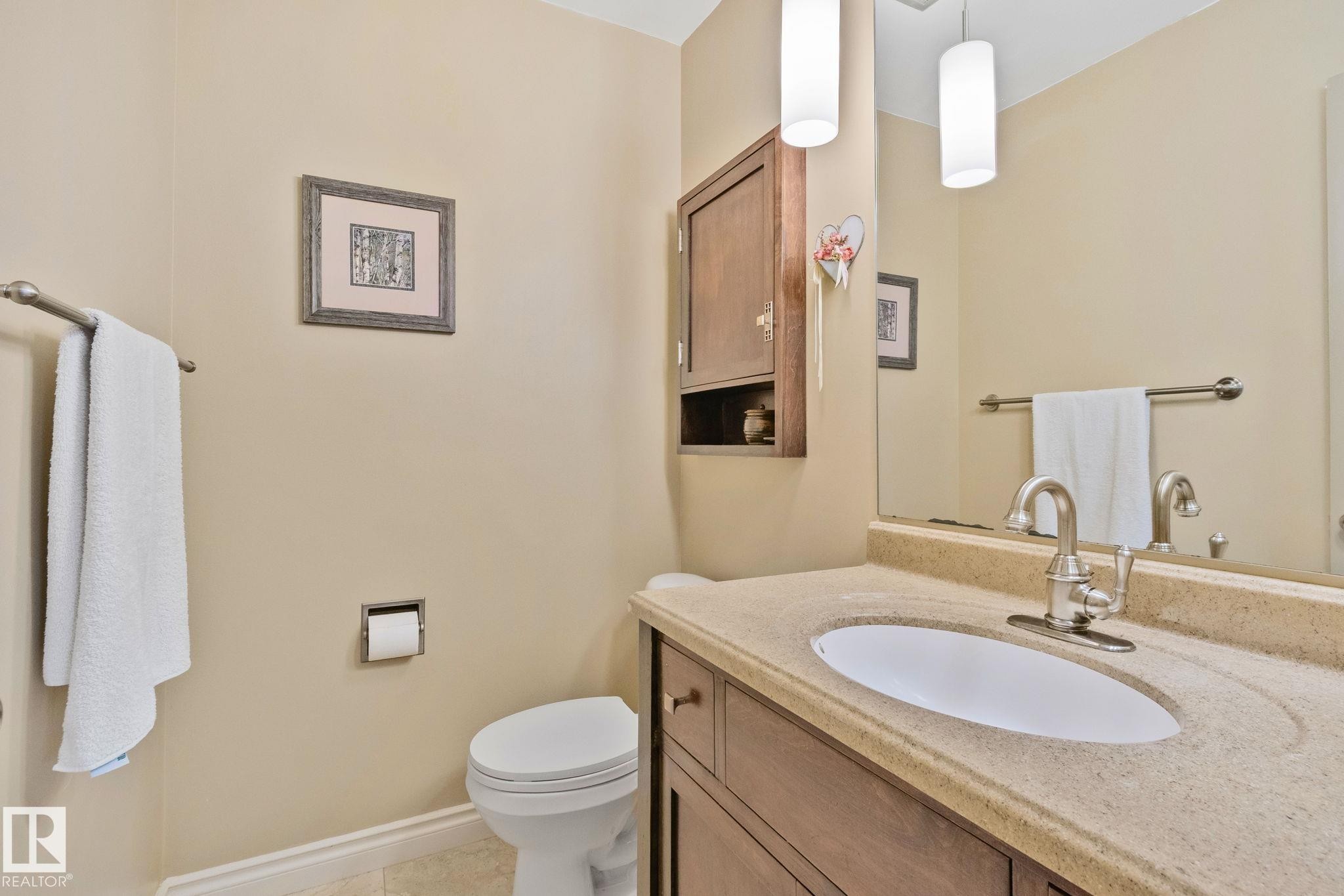Bathroom featuring a vanity with an integrated sink, a large wall mirror, and two pendant light fixtures - 7306 21 Avenue Nw, Edmonton, AB - Indoor Photo Showing Bathroom