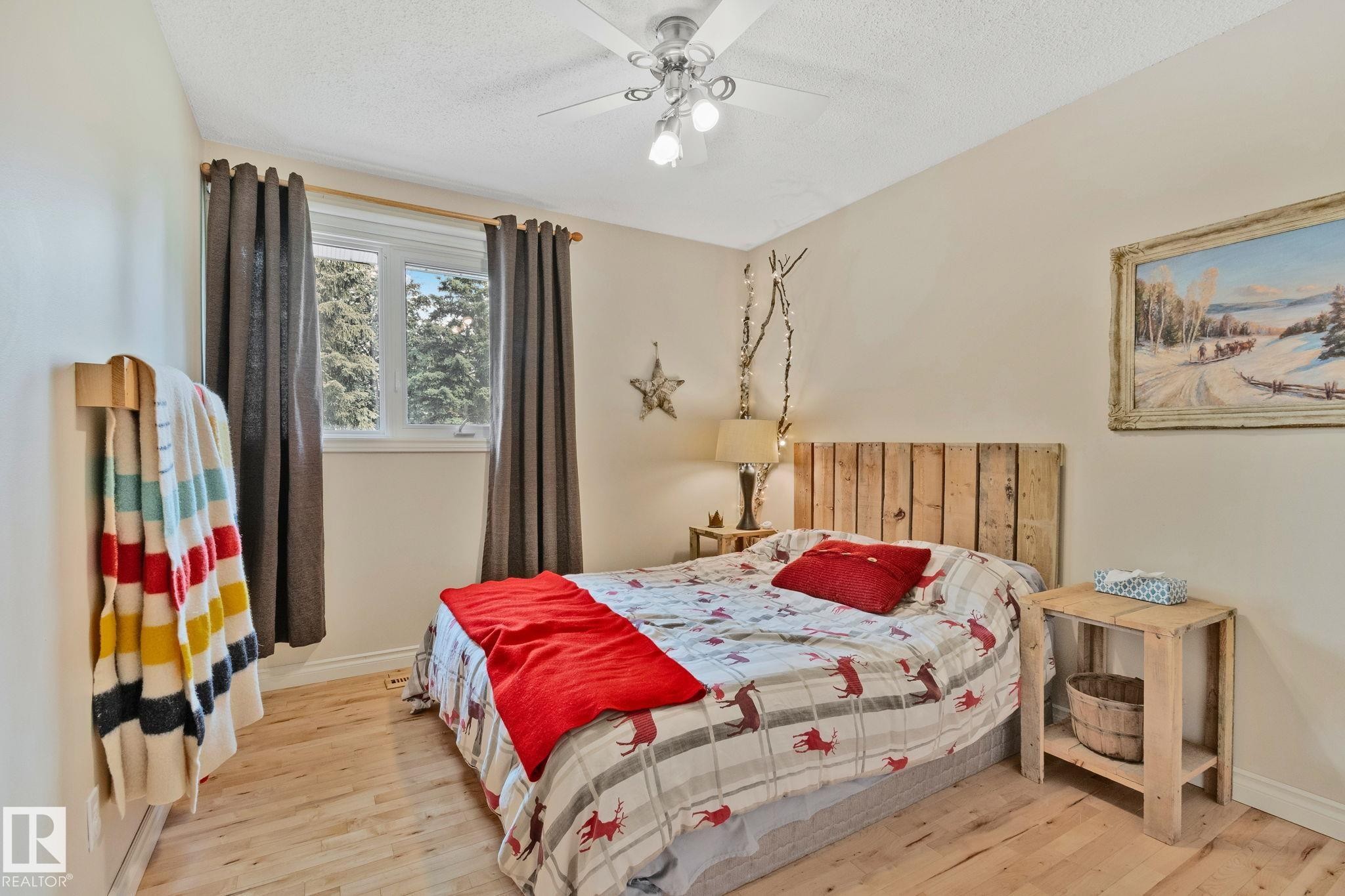 Bedroom featuring wood-finish flooring, a bright window, and a ceiling fan with integrated lighting - 7306 21 Avenue Nw, Edmonton, AB - Indoor Photo Showing Bedroom