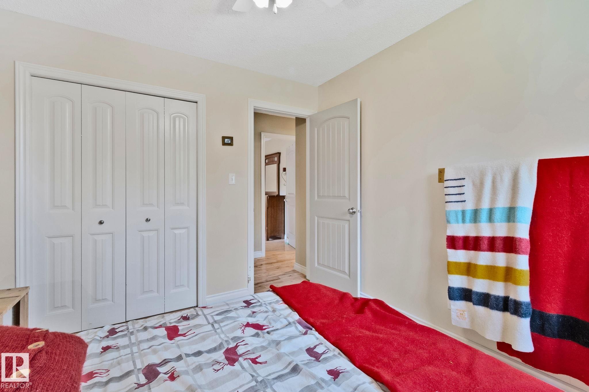 Interior room featuring a white bi-fold closet, light-colored walls, and a ceiling fan - 7306 21 Avenue Nw, Edmonton, AB - Indoor Photo Showing Bedroom