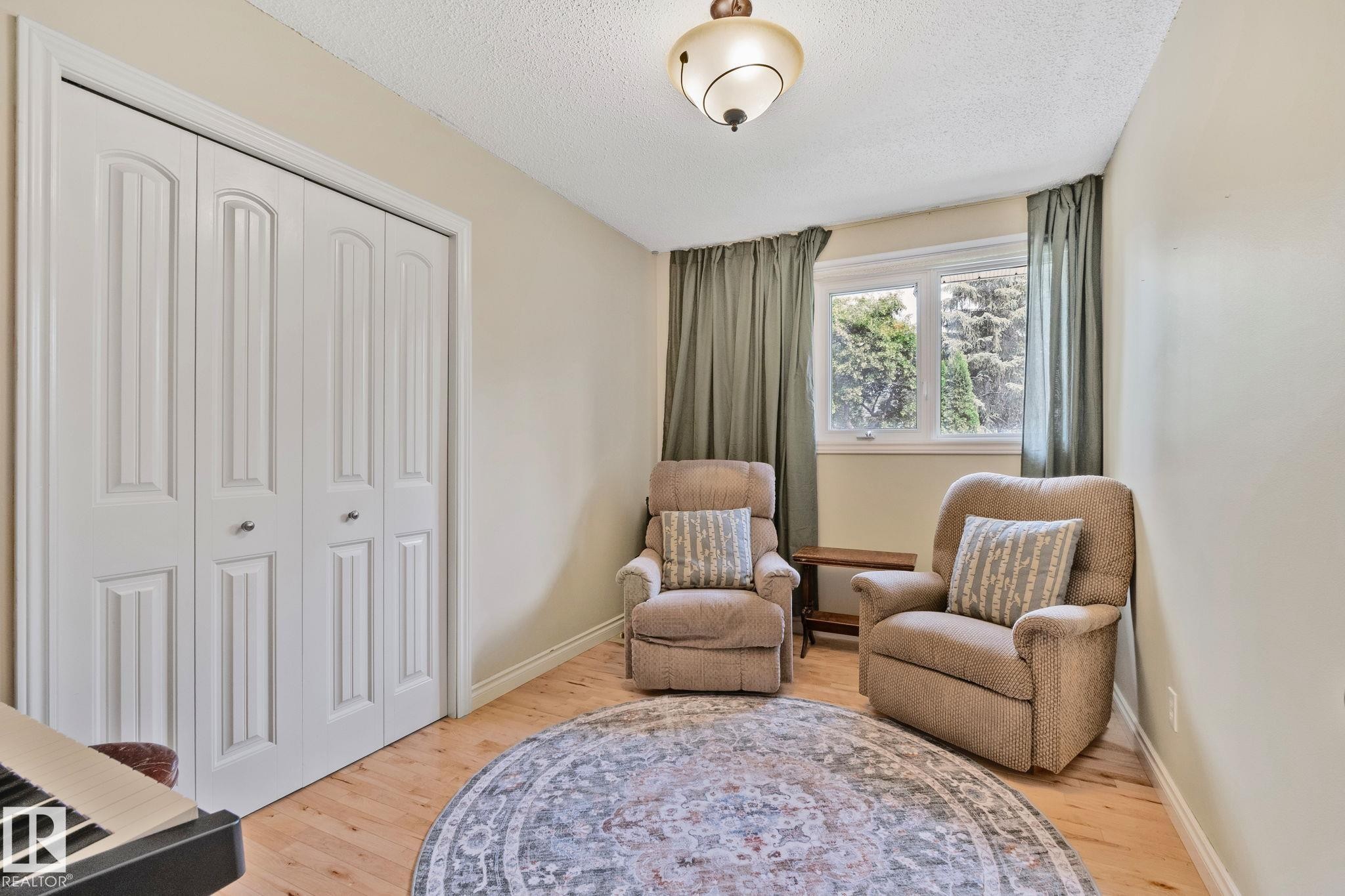 Room featuring light wood-finish flooring, white bifold closet doors, and a double-pane window with surrounding nature - 7306 21 Avenue Nw, Edmonton, AB - Indoor Photo Showing Bedroom