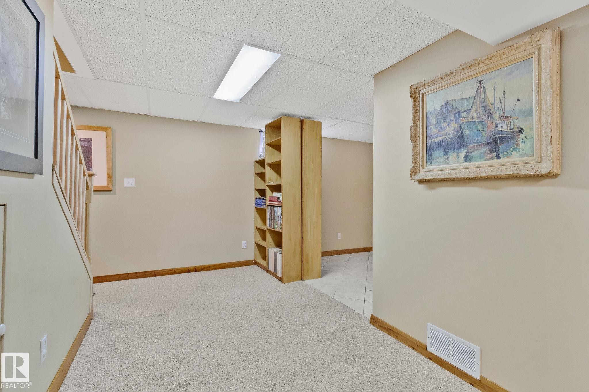 Carpeted floor area with a drop ceiling and integrated fluorescent lighting - 7306 21 Avenue Nw, Edmonton, AB - Indoor Photo Showing Other Room