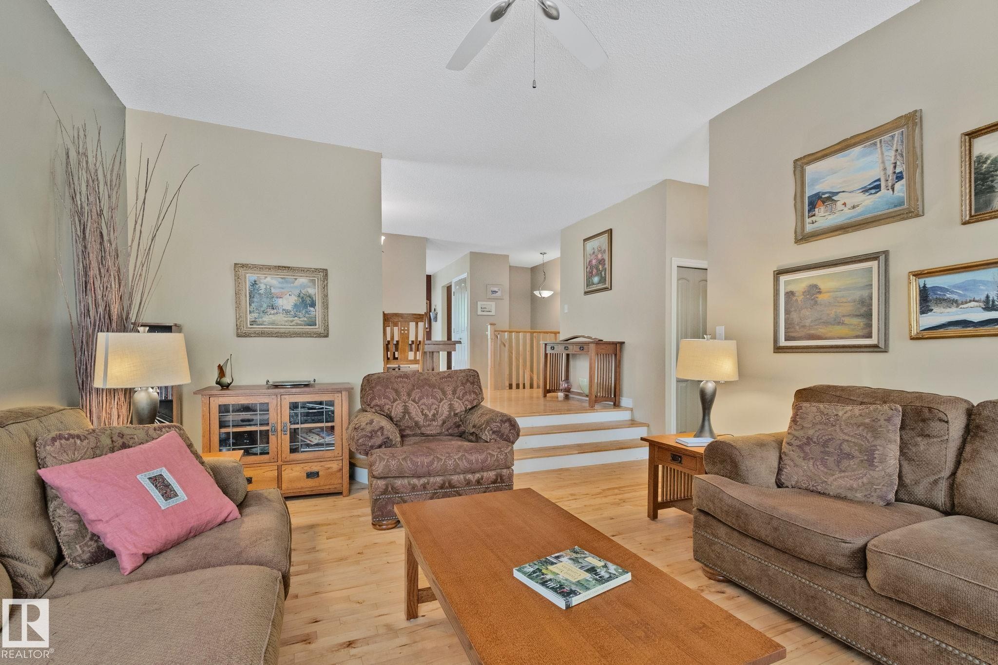 Living room featuring light wood-finish flooring, vaulted ceilings, and a ceiling fan - 7306 21 Avenue Nw, Edmonton, AB - Indoor Photo Showing Living Room