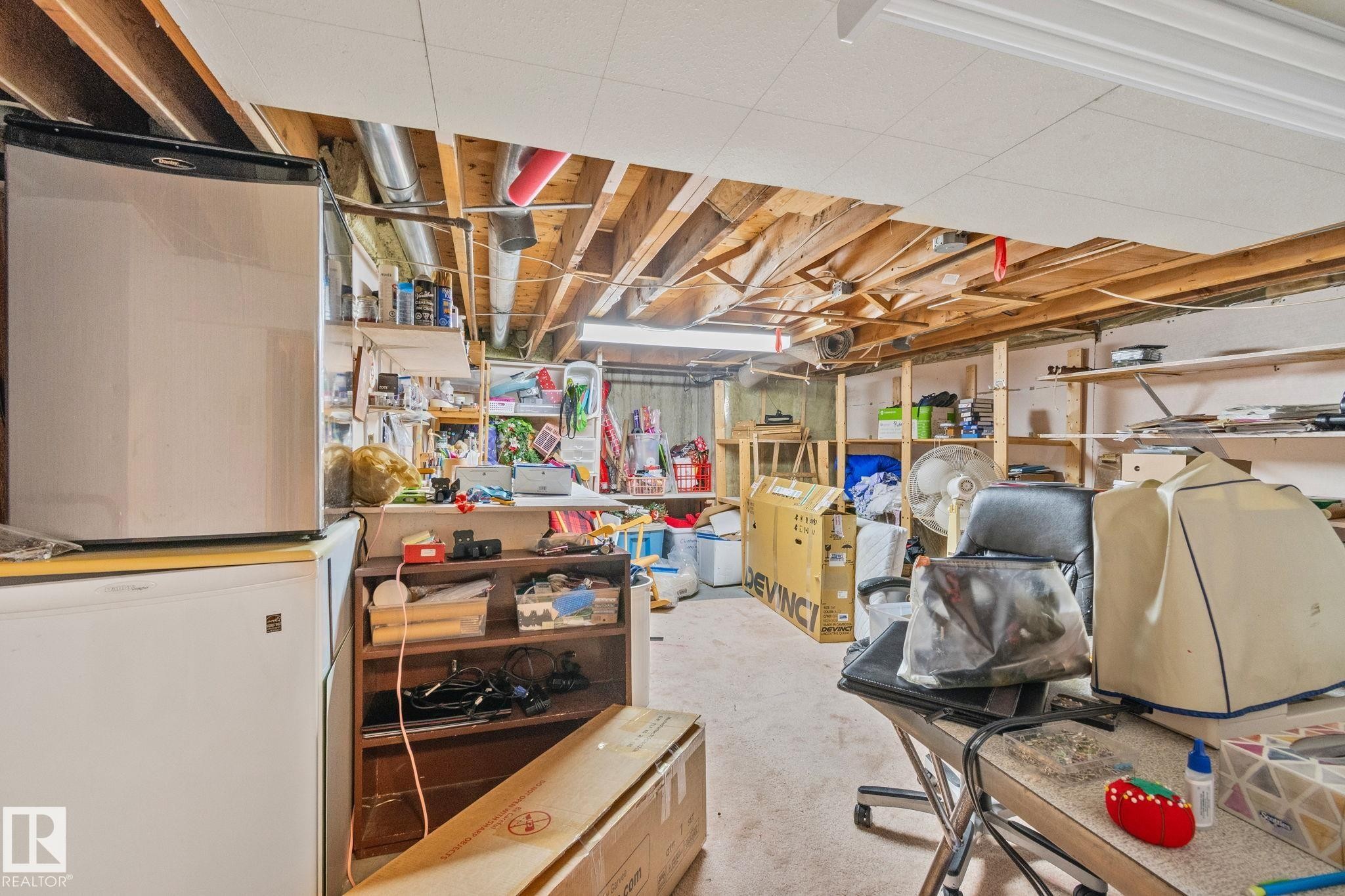 Unfinished basement with exposed ceiling joists, concrete flooring, and ample storage shelving - 7306 21 Avenue Nw, Edmonton, AB - Indoor Photo Showing Basement