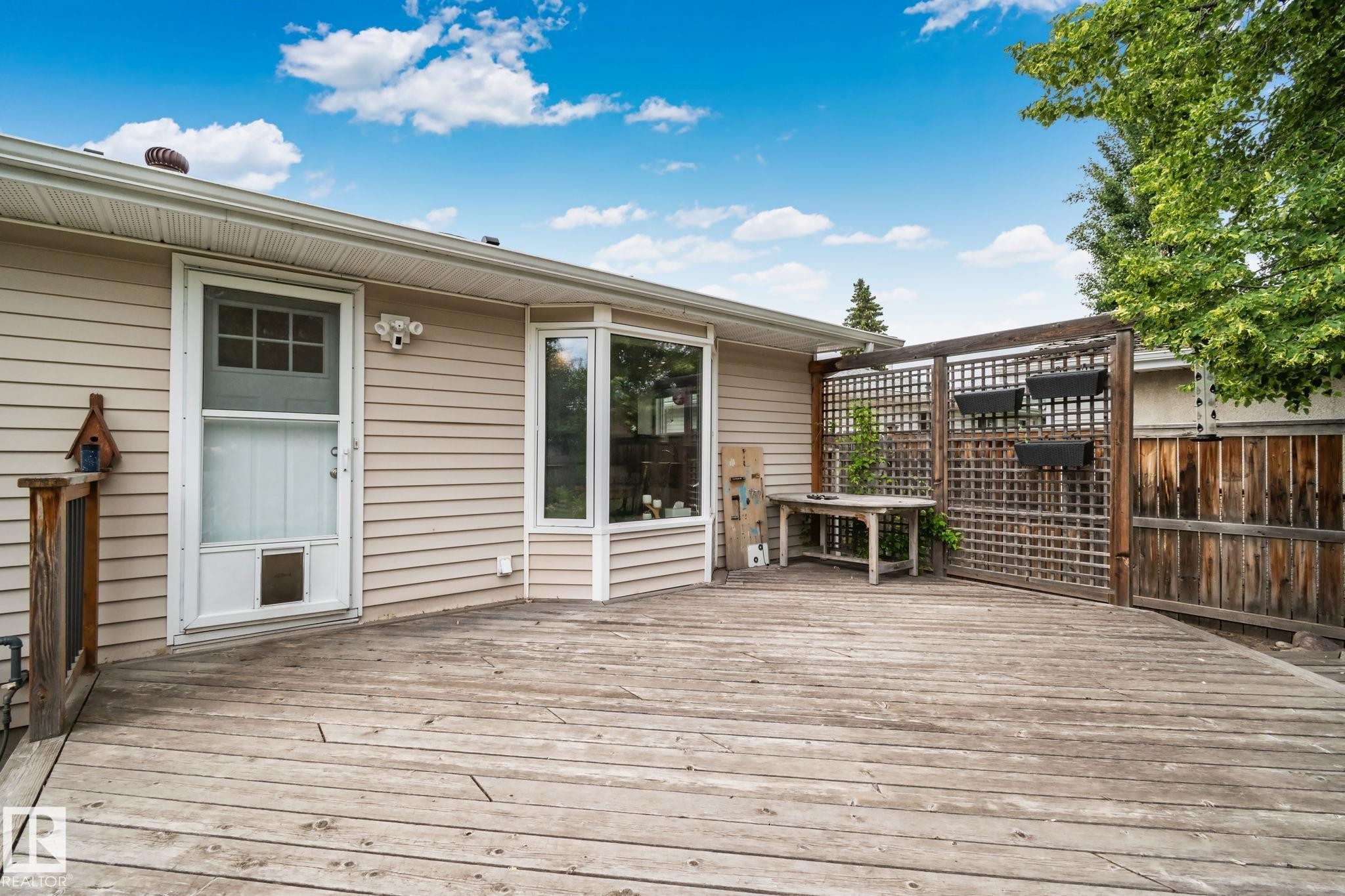Expansive outdoor deck featuring wood flooring and a privacy trellis - 7306 21 Avenue Nw, Edmonton, AB - Outdoor With Exterior