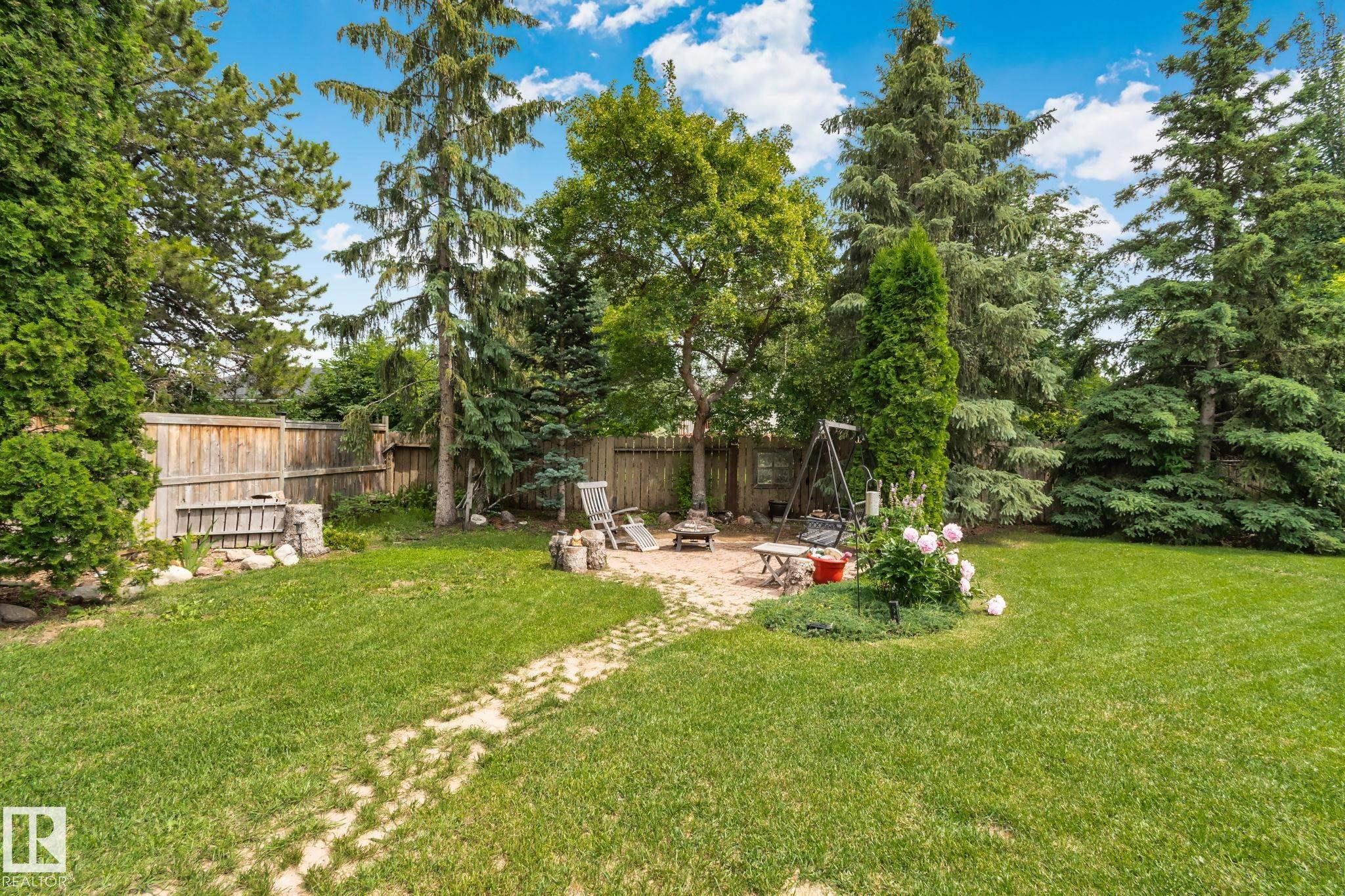 Expansive backyard featuring a large lawn area, mature trees, and a wooden privacy fence - 7306 21 Avenue Nw, Edmonton, AB - Outdoor