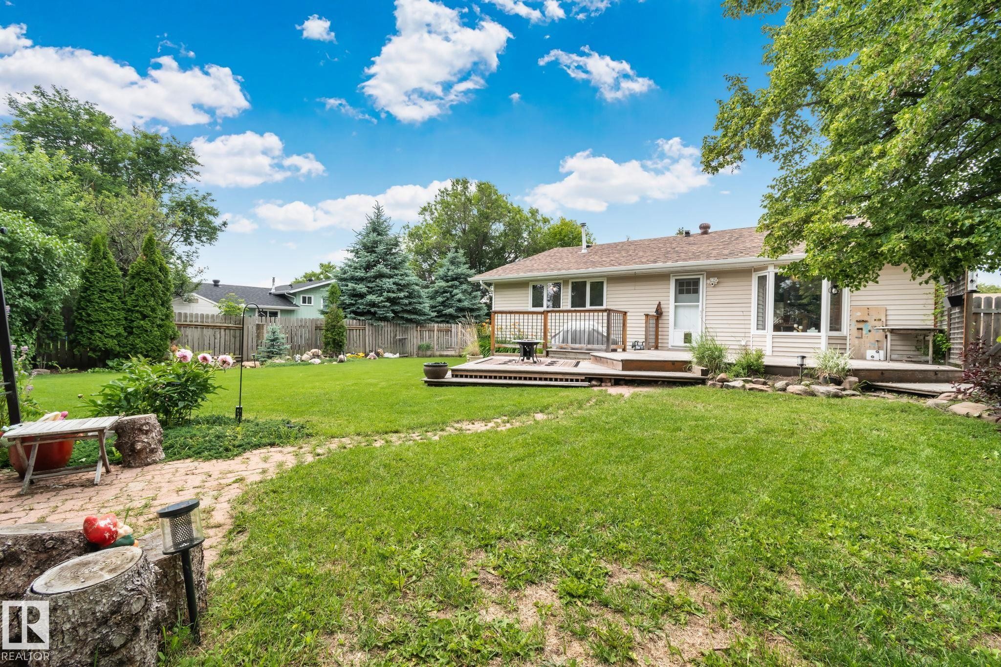 Spacious rear yard with a multi-level wood deck, established trees, and a brick paver pathway - 7306 21 Avenue Nw, Edmonton, AB - Outdoor With Deck Patio Veranda