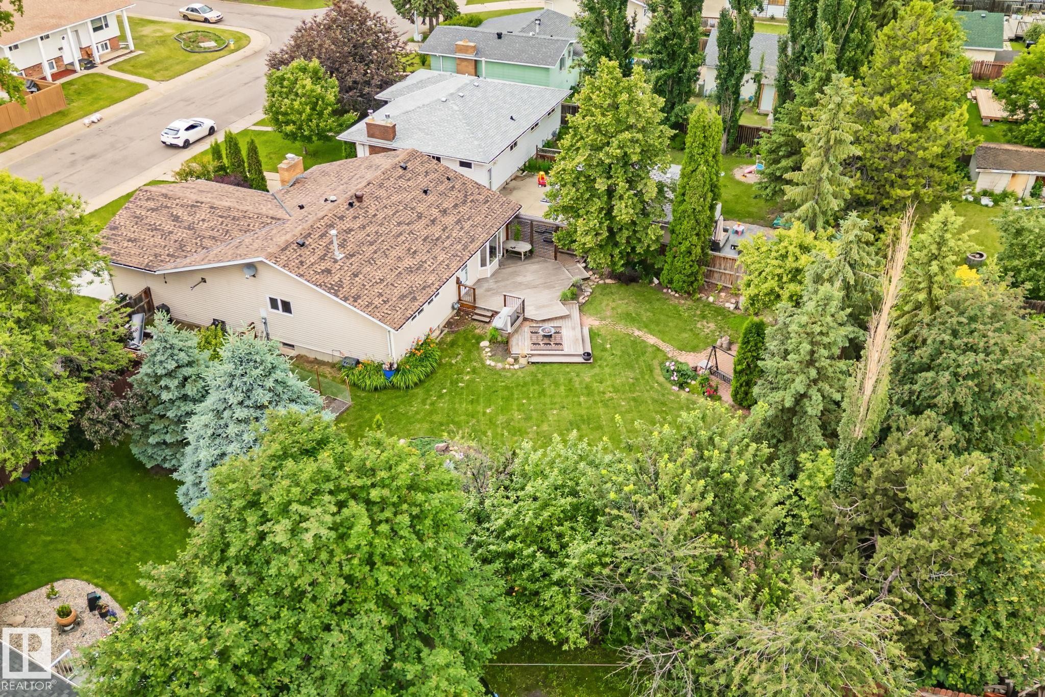 Expansive rear yard featuring a manicured lawn, mature trees, and a spacious patio with a multi-level deck - 7306 21 Avenue Nw, Edmonton, AB - Outdoor