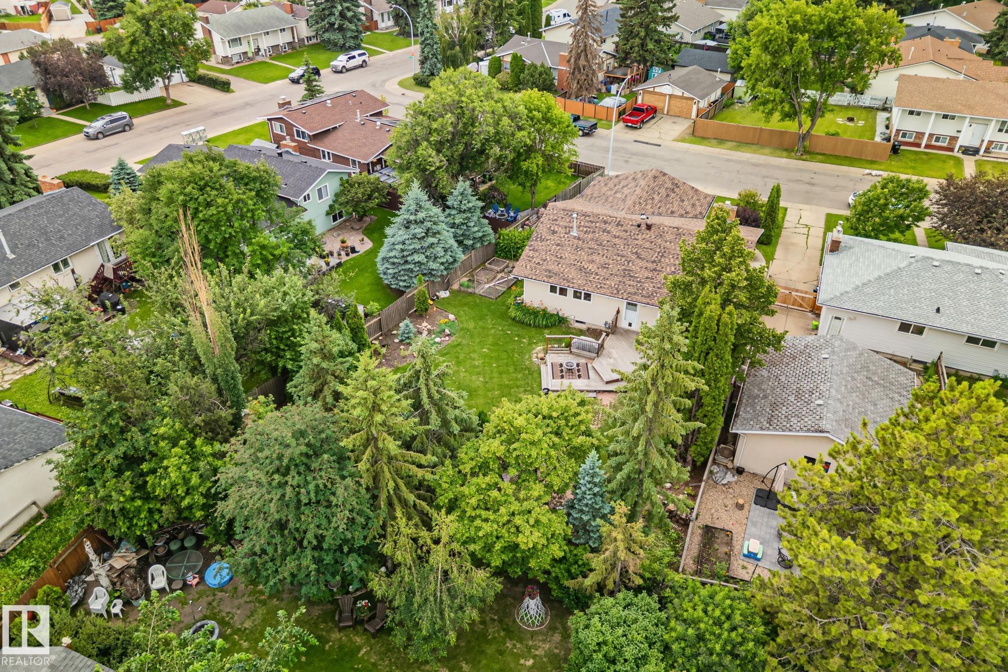 Expansive backyard featuring a manicured lawn, mature trees, and a multi-level wooden deck - 7306 21 Avenue Nw, Edmonton, AB - Outdoor With View