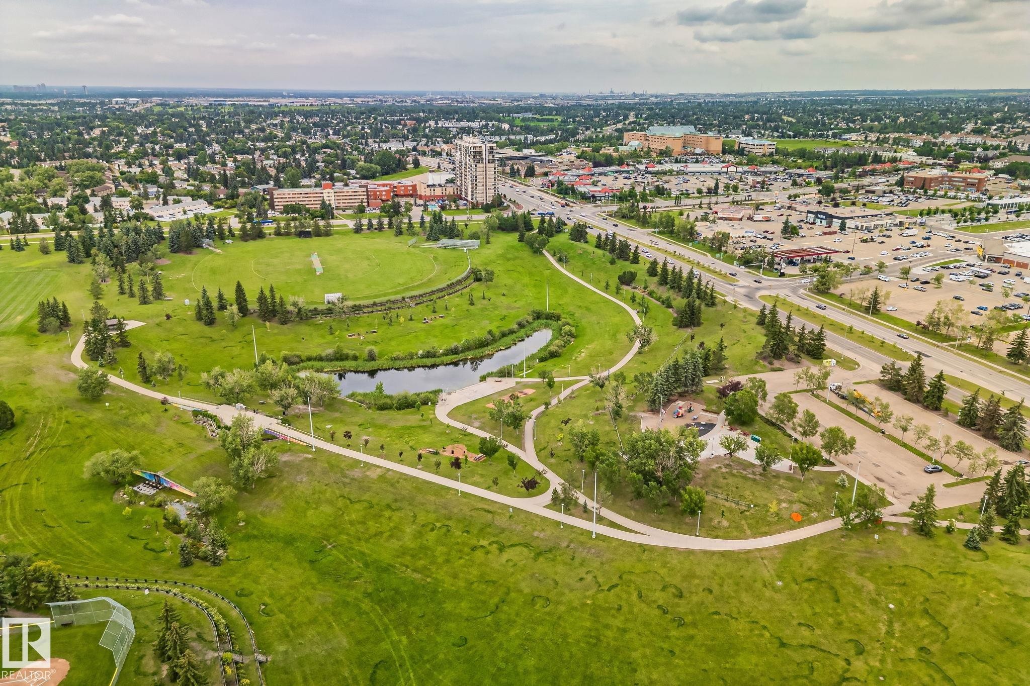 Expansive parkland featuring extensive green spaces, a meandering pond, paved walking paths, numerous mature trees, and nearby commercial developments - 7306 21 Avenue Nw, Edmonton, AB - Outdoor With View