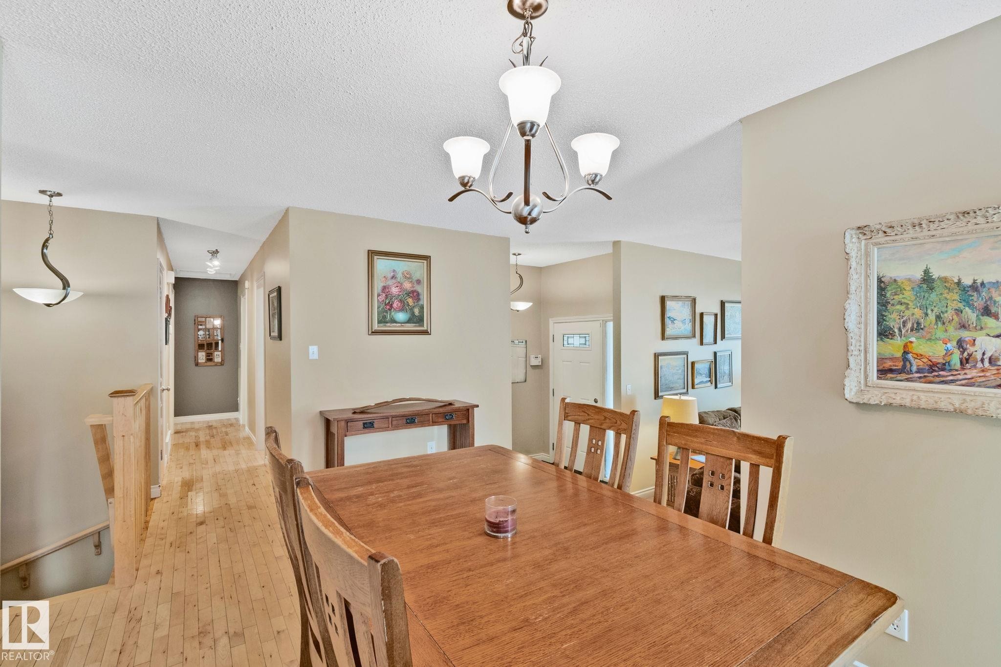 Open-concept dining area featuring wood-finish flooring, a contemporary chandelier, and neutral wall tones - 7306 21 Avenue Nw, Edmonton, AB - Indoor Photo Showing Dining Room