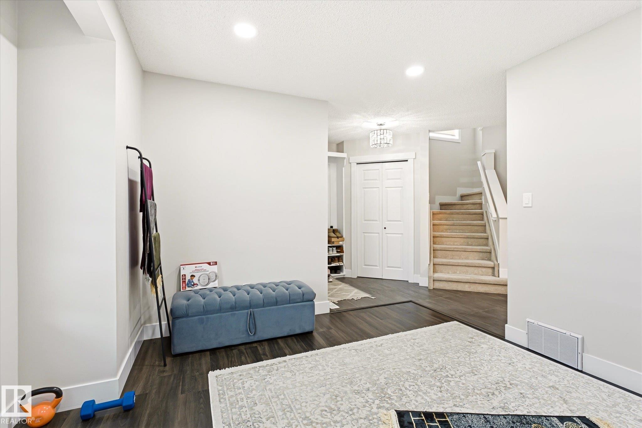 Expansive room featuring wood-finish flooring, recessed lighting, and a white bi-fold door - 4317 152 Avenue Nw, Edmonton, AB - Indoor Photo Showing Other Room