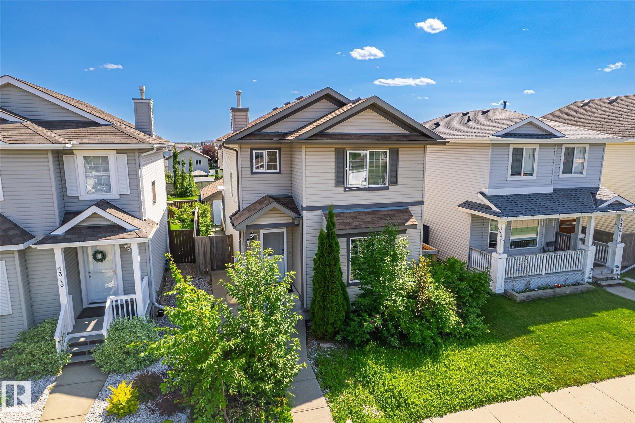 Two-story residence featuring light gray siding, dark trim accents, a front gable, an awning over the front entry, and mature landscaping - 4317 152 Avenue Nw, Edmonton, AB - Outdoor With Deck Patio Veranda With Facade