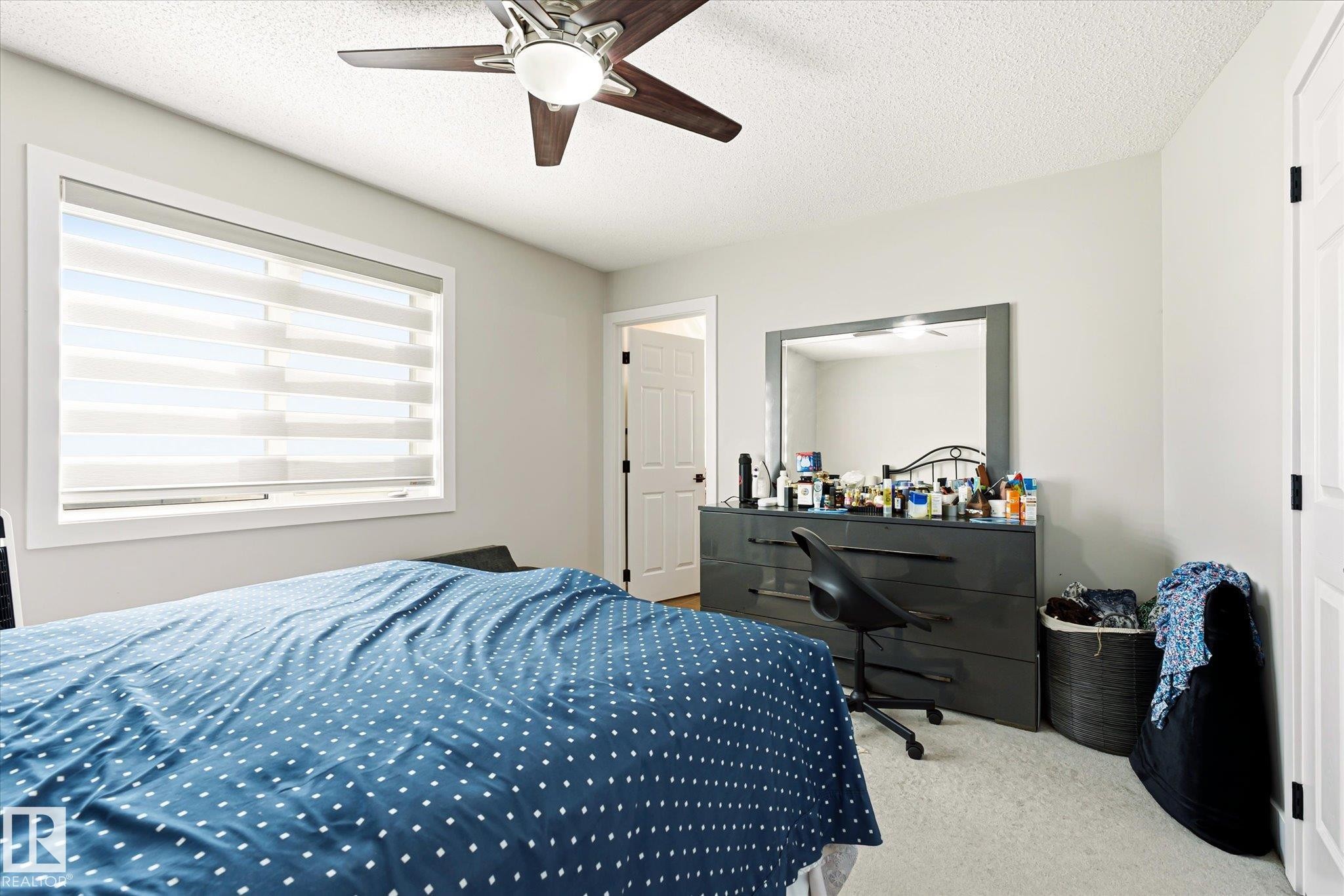 Bright room featuring a window with banded shades, light-colored walls, and a ceiling fan with integrated lighting - 4317 152 Avenue Nw, Edmonton, AB - Indoor Photo Showing Bedroom
