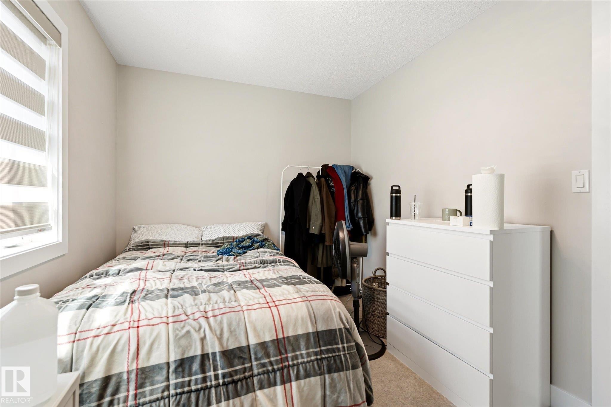 Neutral-toned bedroom featuring a window with horizontal blinds and light-colored carpeting - 4317 152 Avenue Nw, Edmonton, AB - Indoor Photo Showing Bedroom