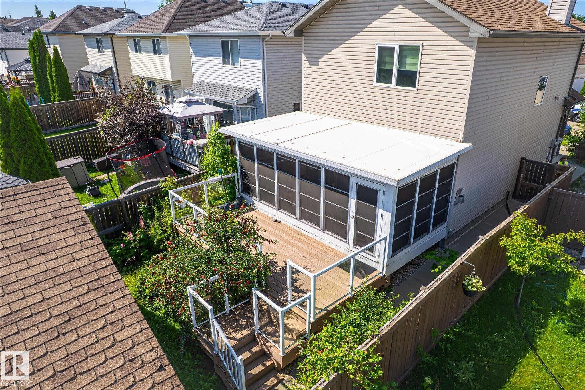 Rear exterior featuring a screened-in porch with a wood-finish deck and glass panel railings - 4317 152 Avenue Nw, Edmonton, AB - Outdoor With Exterior