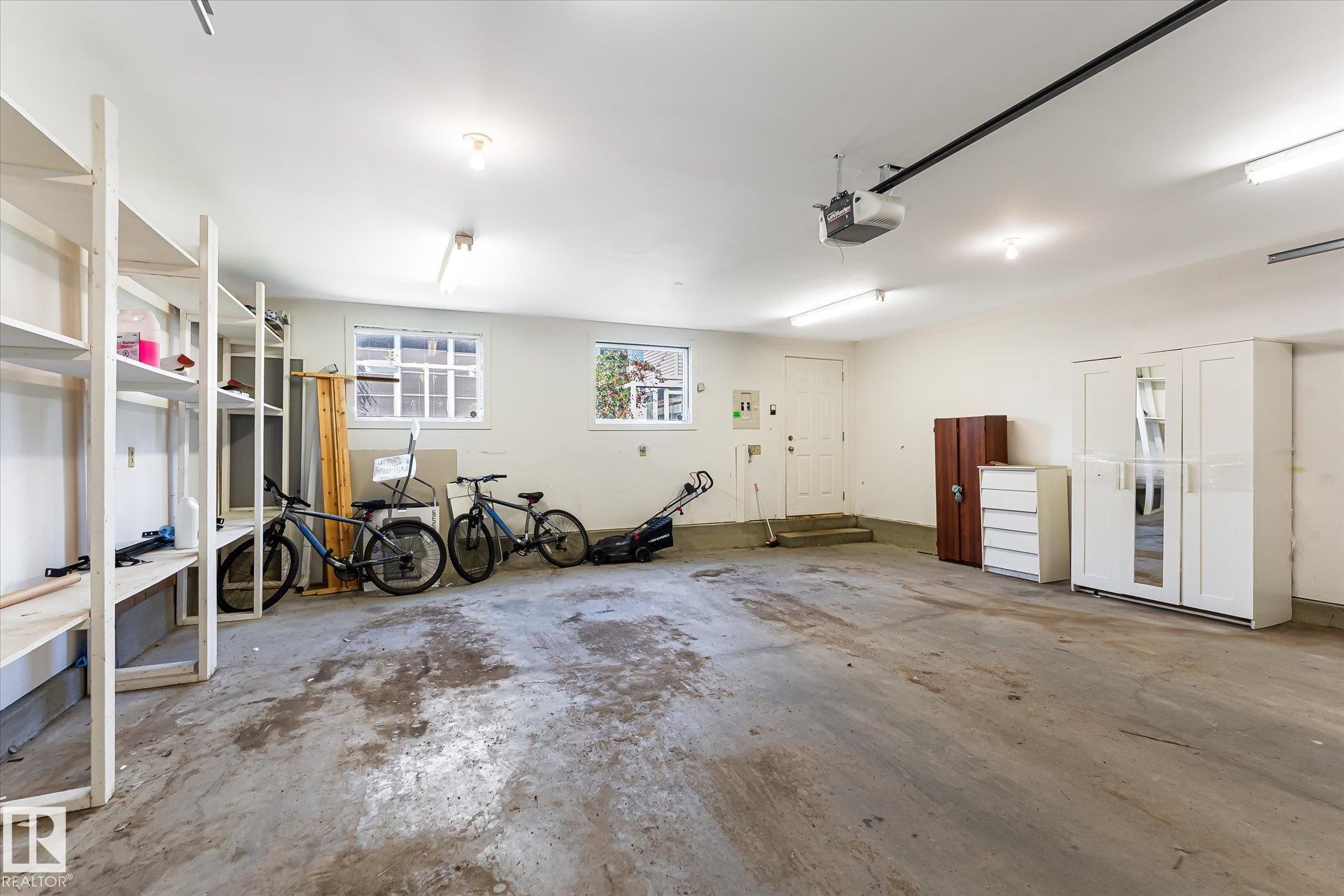 Spacious garage featuring concrete flooring and exposed ceiling beams - 4317 152 Avenue Nw, Edmonton, AB - Indoor Photo Showing Garage