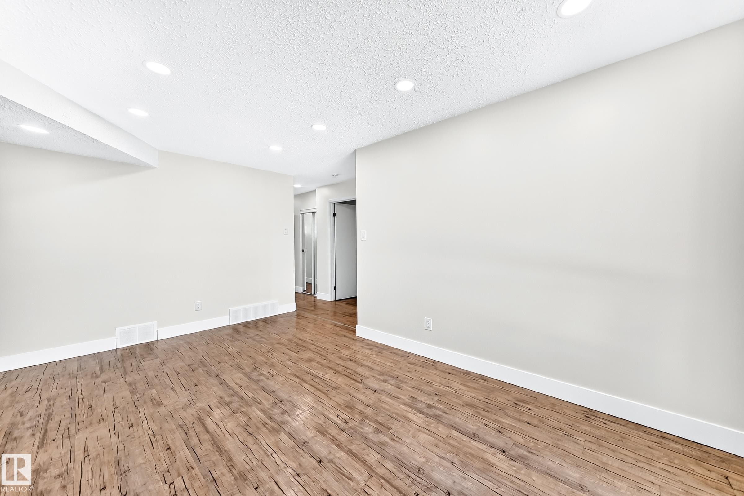 Spacious room featuring wood-finish flooring, recessed lighting, and crisp white baseboards - 3119 144 Avenue Nw, Edmonton, AB - Indoor Photo Showing Other Room