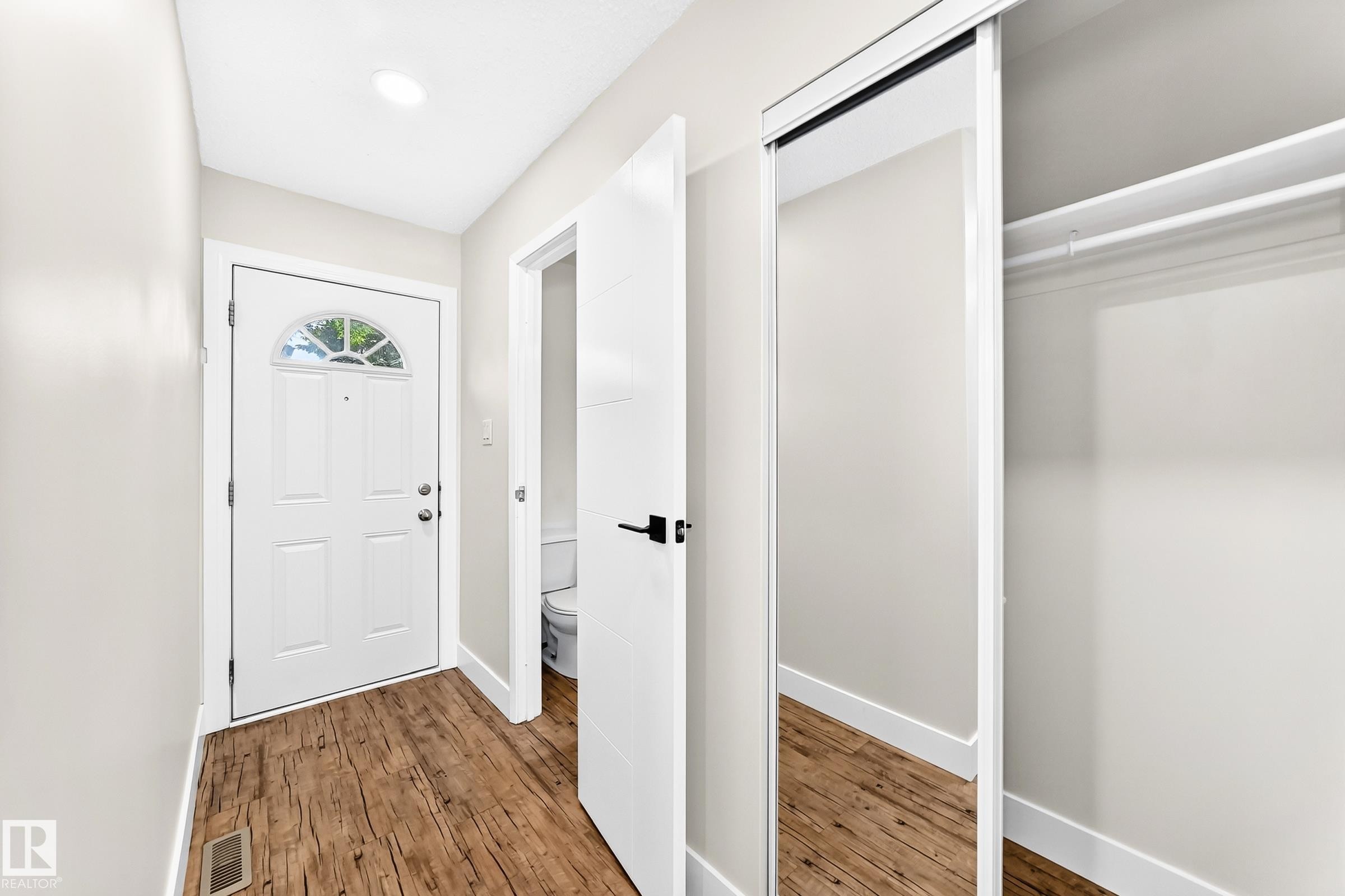 Entryway featuring wood-finish flooring, a white paneled entry door with an arched window, and a recessed ceiling light - 3119 144 Avenue Nw, Edmonton, AB - Indoor Photo Showing Other Room