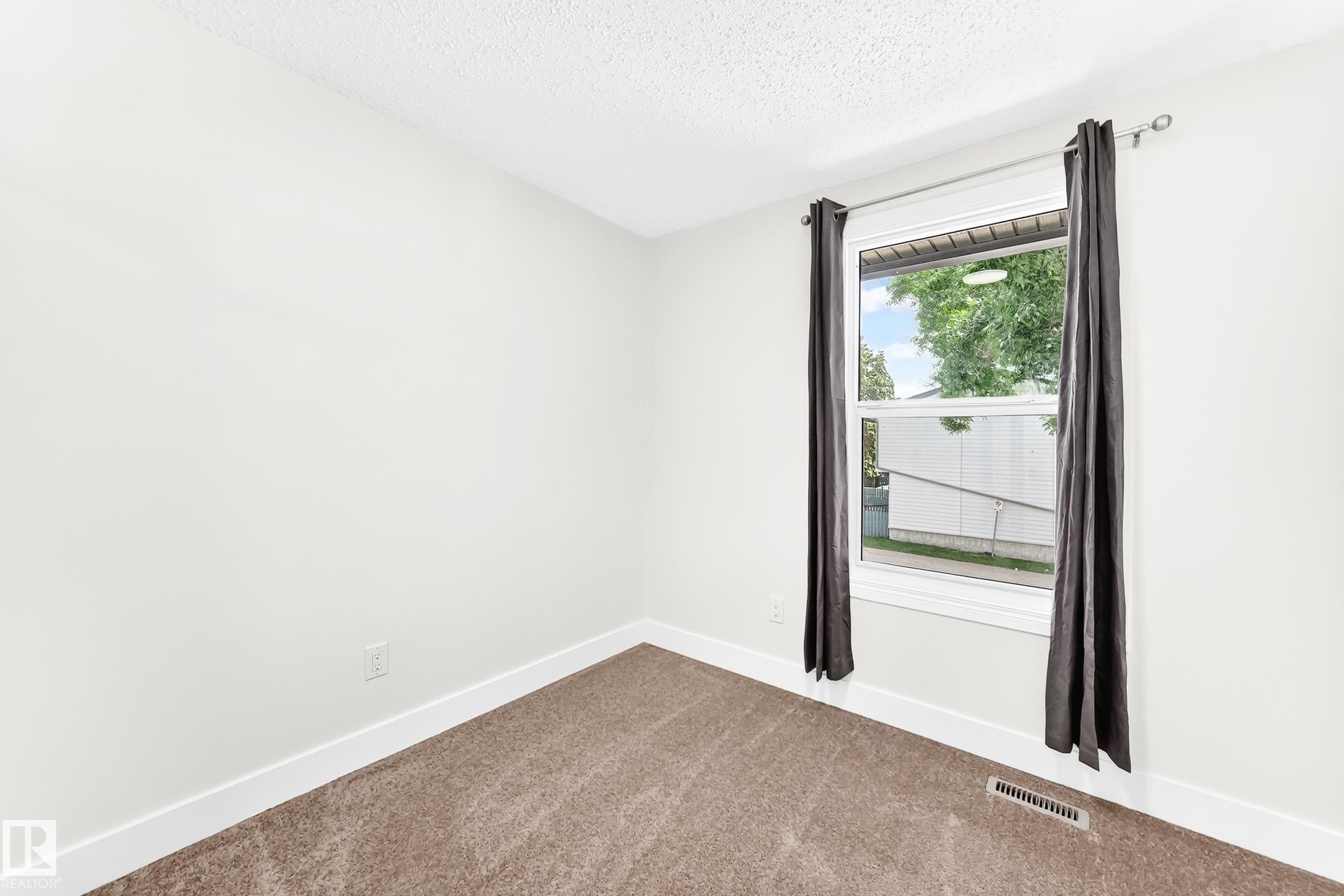 Carpeted room featuring a single window with white trim, a floor vent, and a textured white ceiling - 3119 144 Avenue Nw, Edmonton, AB - Indoor Photo Showing Other Room