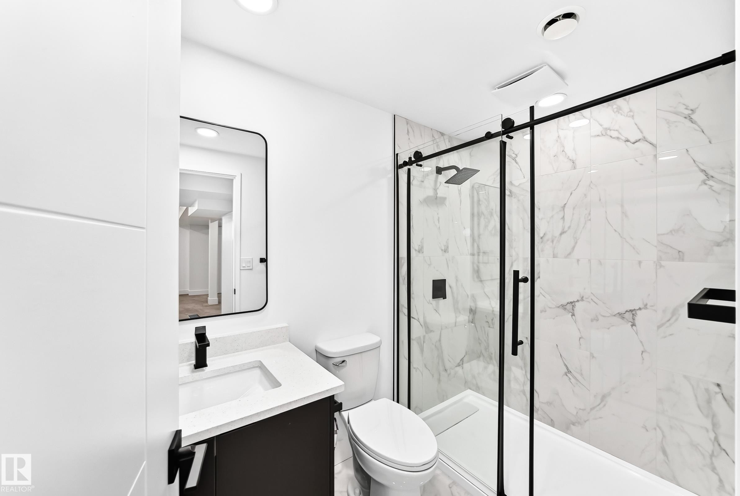 Bathroom featuring a glass-enclosed shower with black trim, a large format marbled tile surround, a built-in shower niche, and a rain shower head - 3119 144 Avenue Nw, Edmonton, AB - Indoor Photo Showing Bathroom