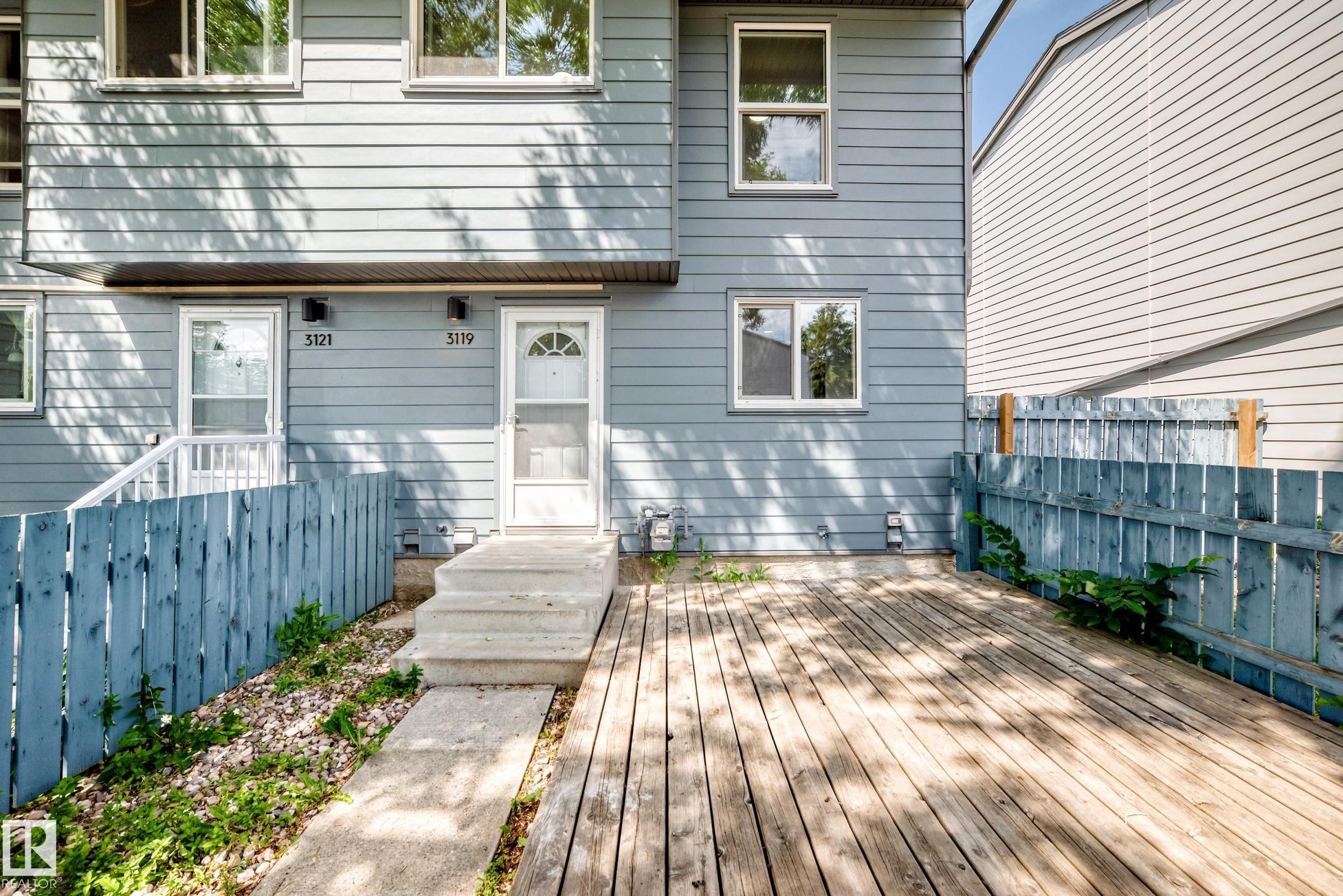 Exterior featuring light blue siding with white trim windows and a front entrance with a screen door - 3119 144 Avenue Nw, Edmonton, AB - Outdoor With Deck Patio Veranda With Exterior