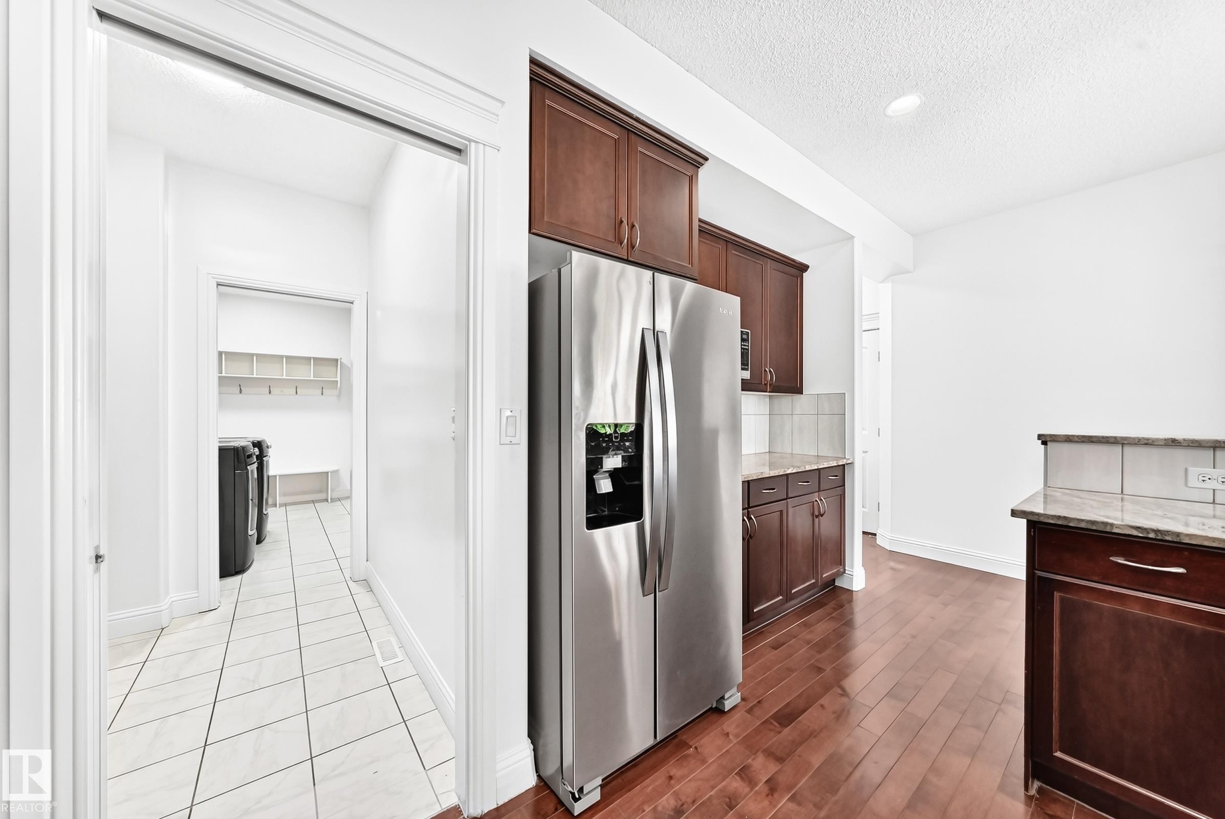 Kitchen featuring stainless steel appliances, wood-finish flooring, and dark wood cabinetry with granite countertops - 1663 Rutherford Road Sw, Edmonton, AB - Indoor Photo Showing Kitchen