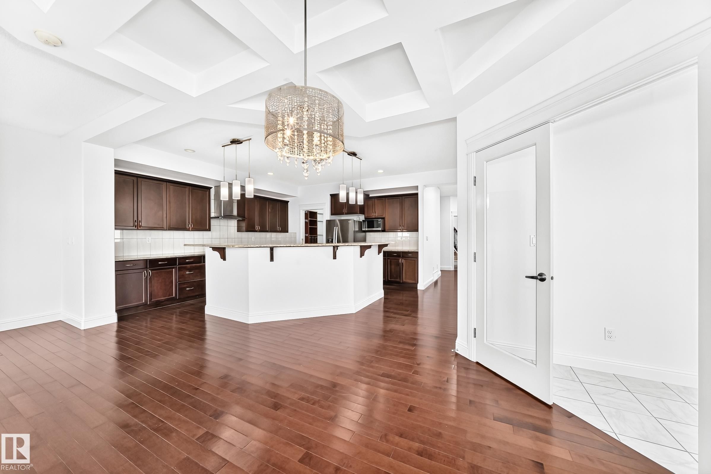 Open-concept living space featuring wood-finish flooring, a coffered ceiling, and a prominent crystal chandelier - 1663 Rutherford Road Sw, Edmonton, AB - Indoor Photo Showing Kitchen