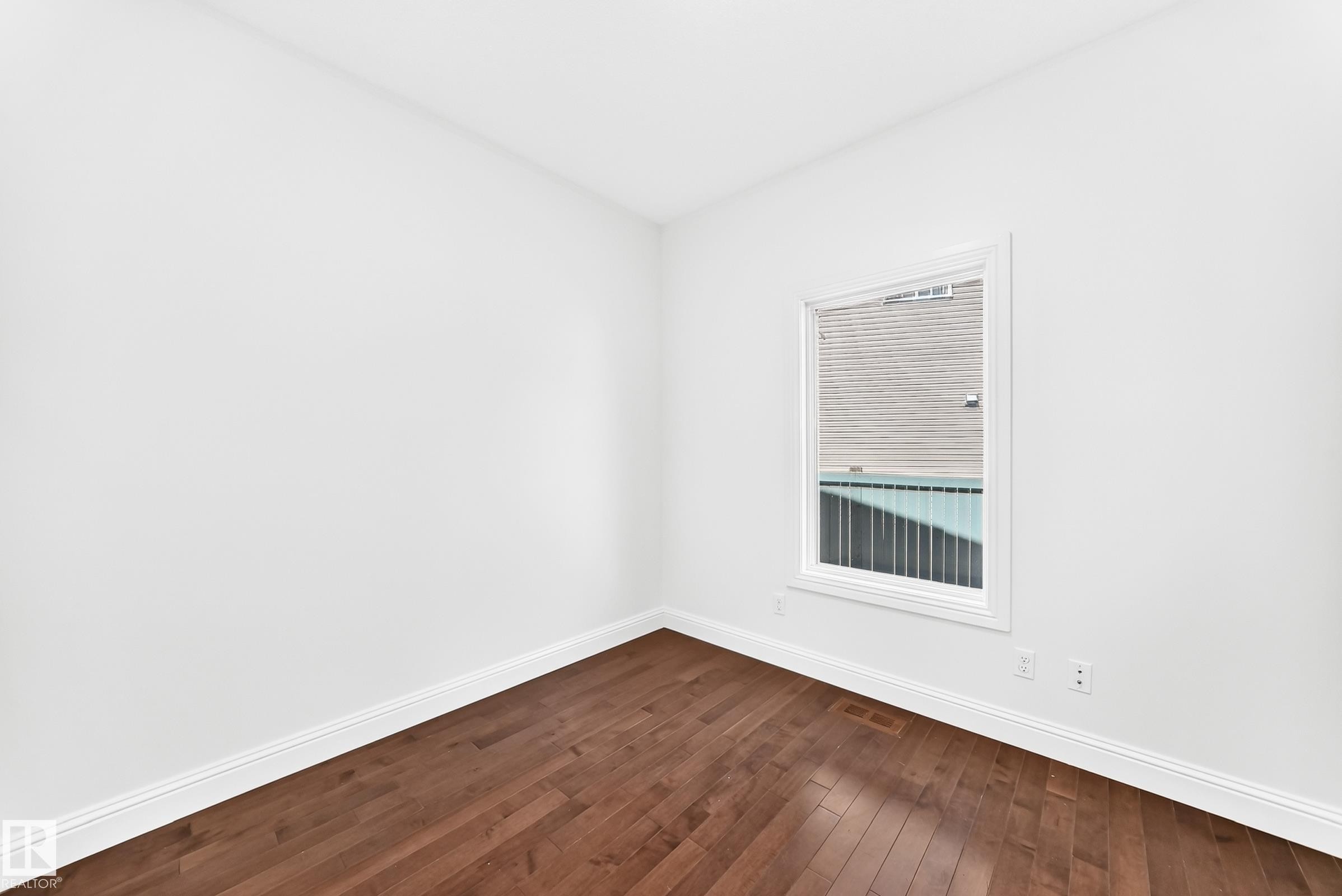 Bright room featuring wood-finish flooring, white baseboards, and a single window with white trim - 1663 Rutherford Road Sw, Edmonton, AB - Indoor Photo Showing Other Room
