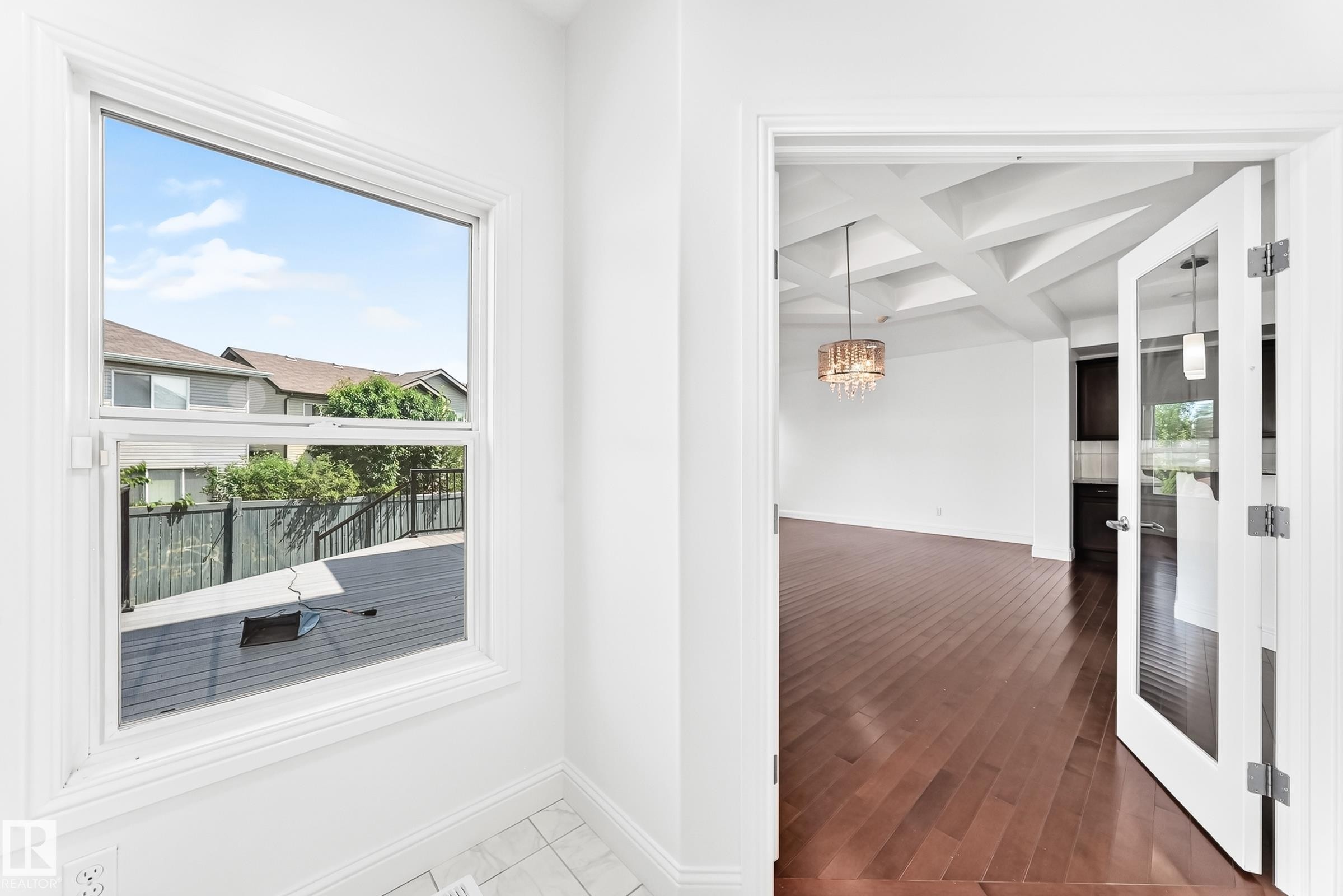 White-framed window overlooking a dark-stained deck with black railings - 1663 Rutherford Road Sw, Edmonton, AB - Indoor Photo Showing Other Room