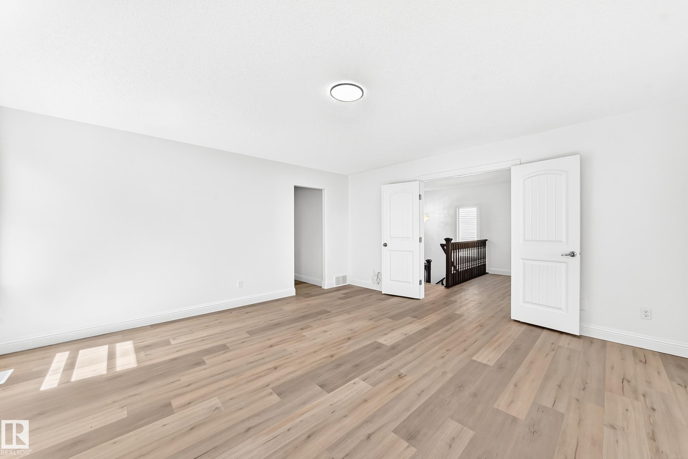 Spacious room featuring light wood-finish flooring, crisp white walls, and a recessed ceiling light - 1663 Rutherford Road Sw, Edmonton, AB - Indoor Photo Showing Other Room