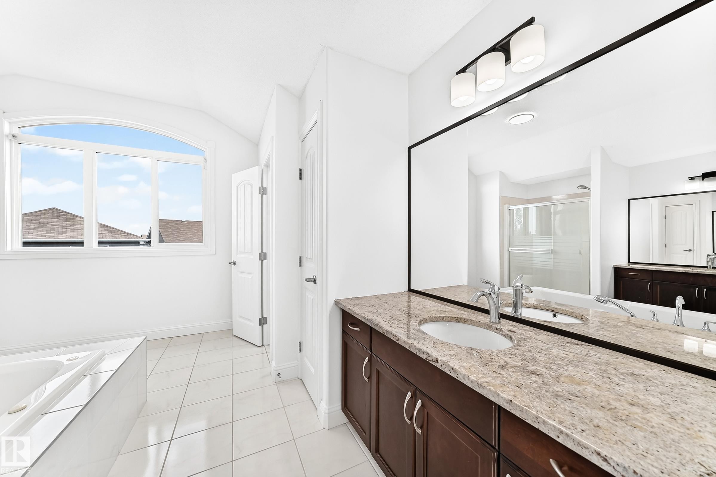 Spacious bathroom featuring a dual vanity with light-toned stone countertops and dark wood cabinetry - 1663 Rutherford Road Sw, Edmonton, AB - Indoor Photo Showing Bathroom