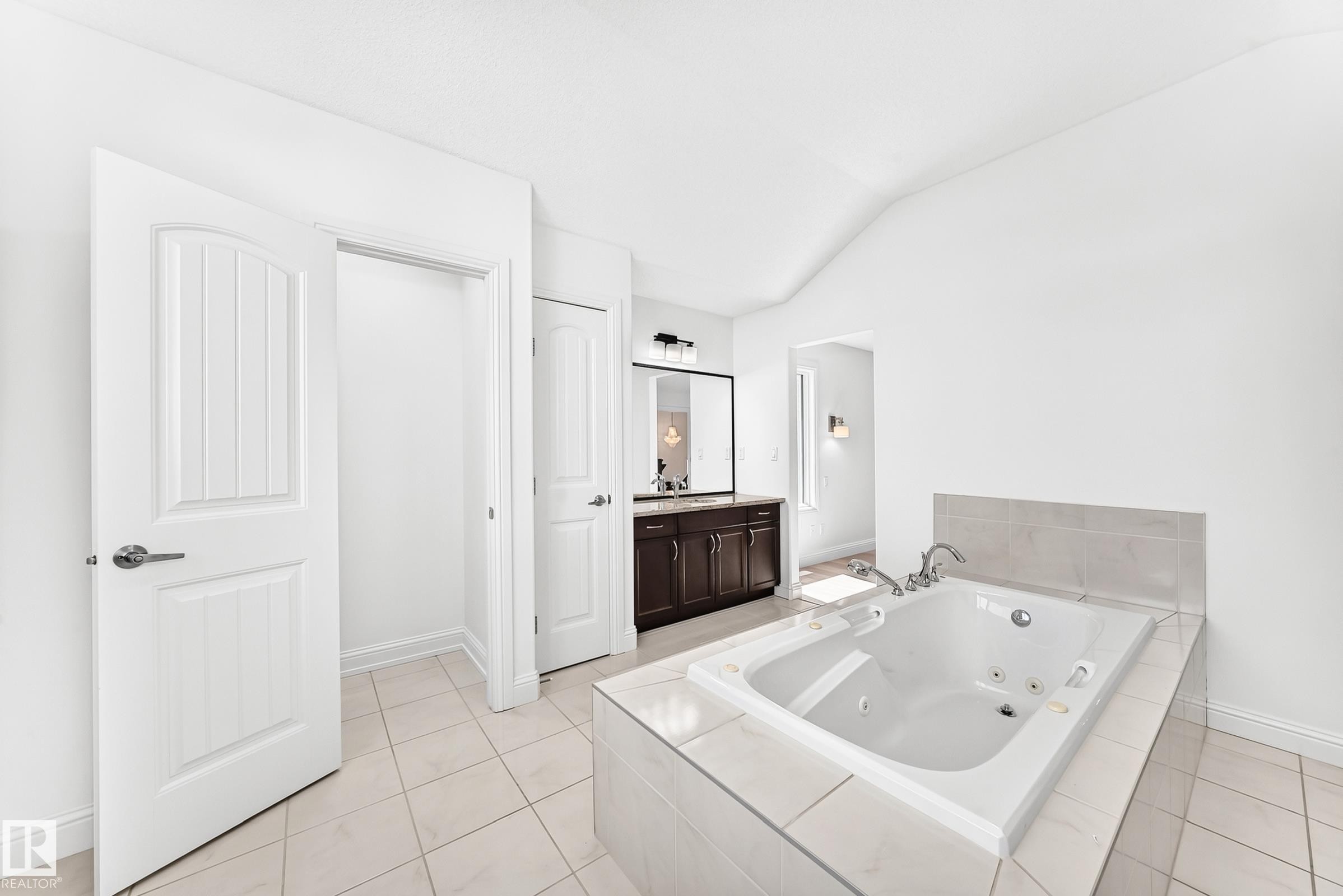 Soaking tub set in a tiled surround with a light tile backsplash - 1663 Rutherford Road Sw, Edmonton, AB - Indoor Photo Showing Bathroom