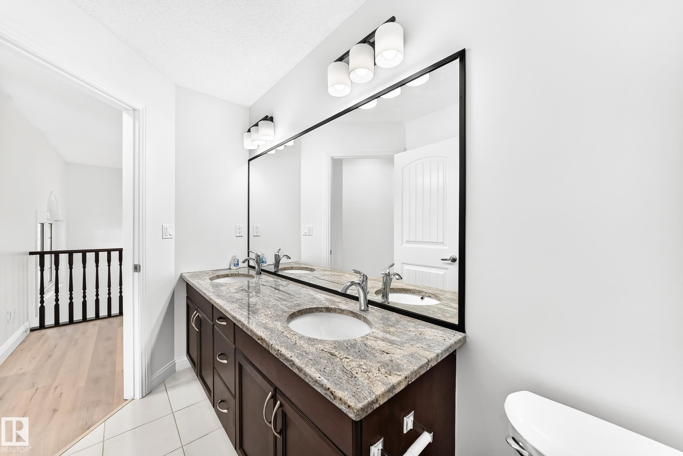 Dual vanity with a stone countertop, undermount sinks, and ample storage cabinetry - 1663 Rutherford Road Sw, Edmonton, AB - Indoor Photo Showing Bathroom