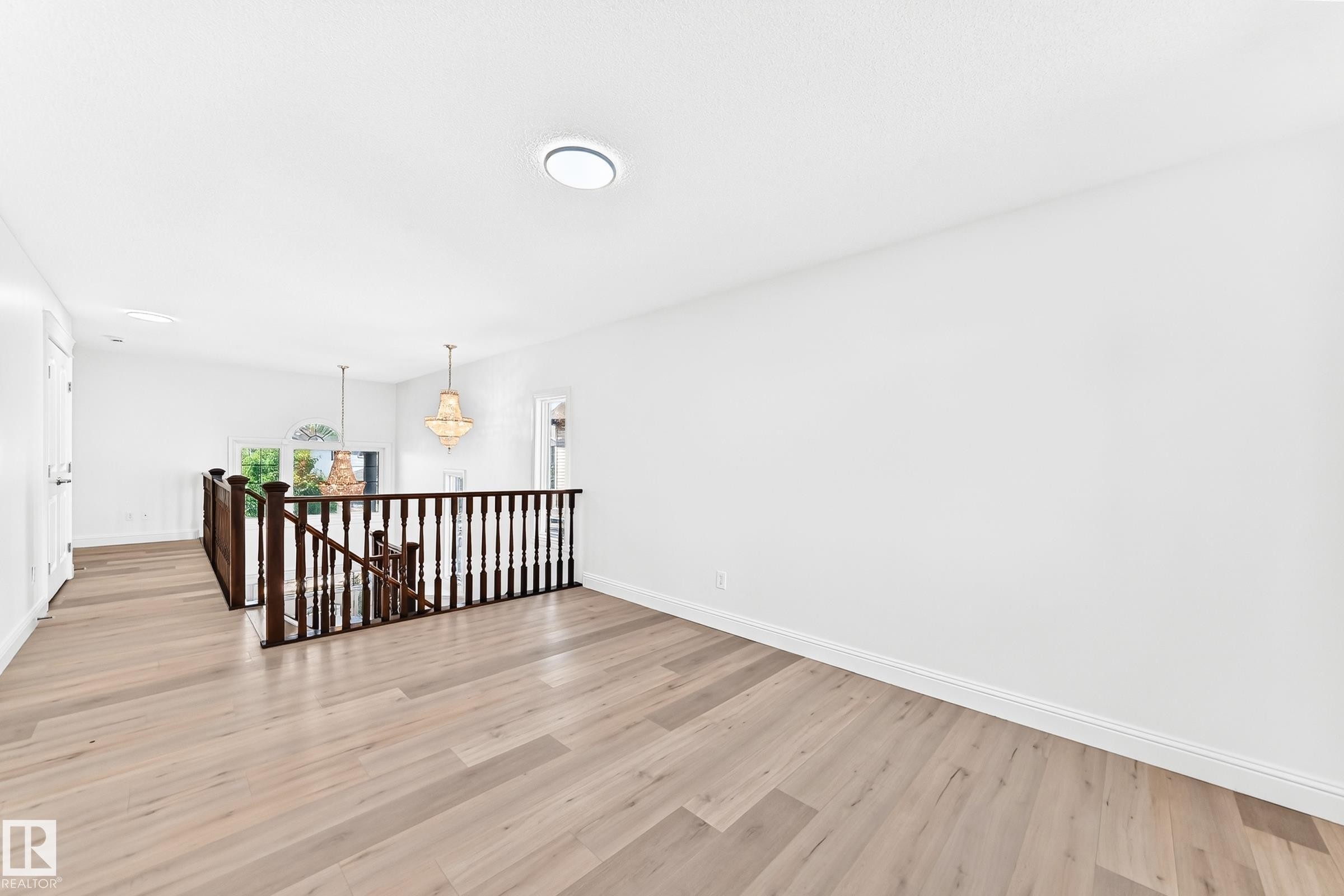 Upper-level landing featuring light wood-finish flooring, white walls, and a dark wood staircase railing - 1663 Rutherford Road Sw, Edmonton, AB - Indoor Photo Showing Other Room