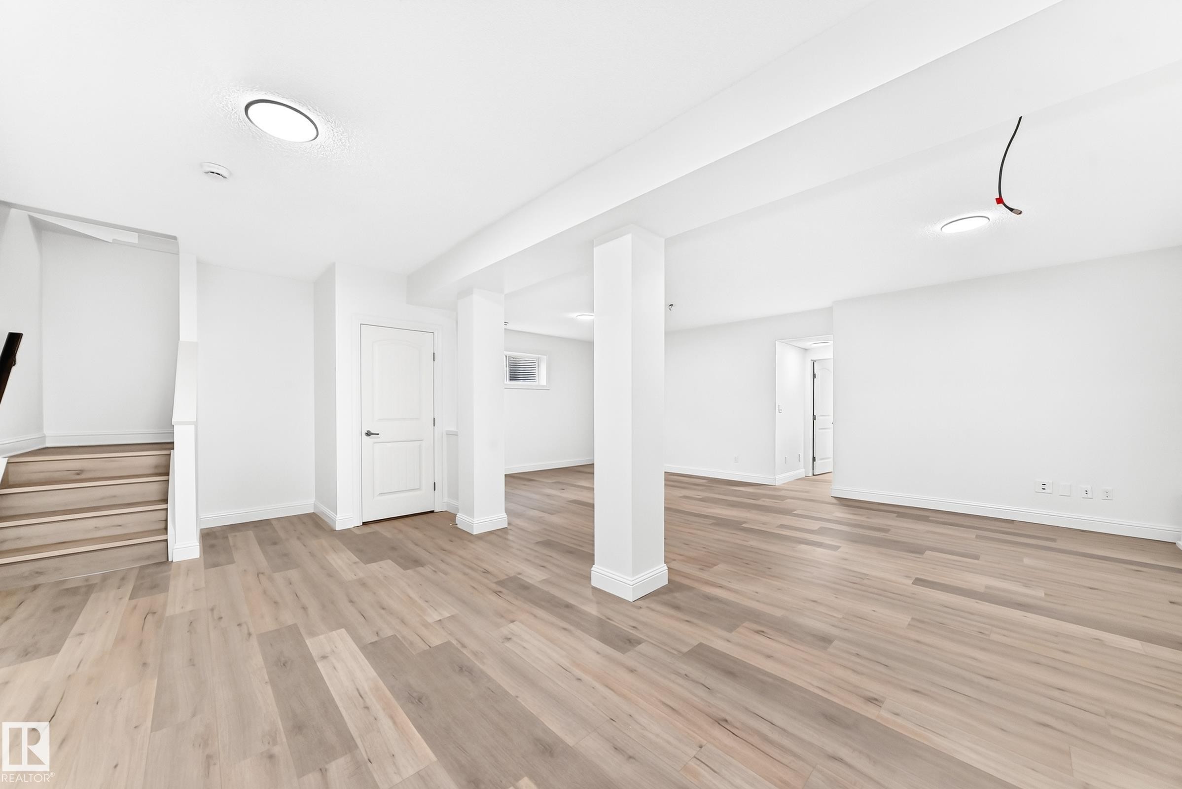 Open-concept lower level featuring light wood-finish flooring, white painted walls, recessed lighting, and a window - 1663 Rutherford Road Sw, Edmonton, AB - Indoor Photo Showing Other Room