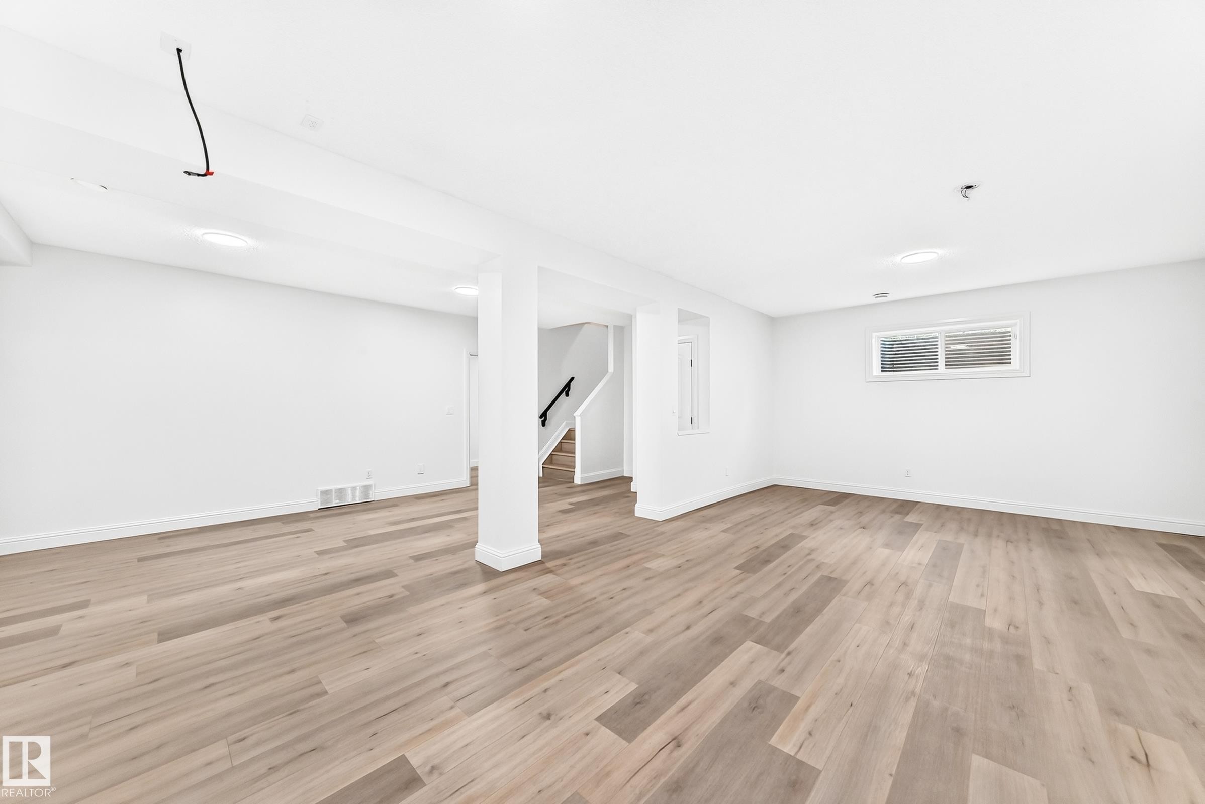 Spacious room featuring wood-finish flooring, white walls, and recessed lighting - 1663 Rutherford Road Sw, Edmonton, AB - Indoor