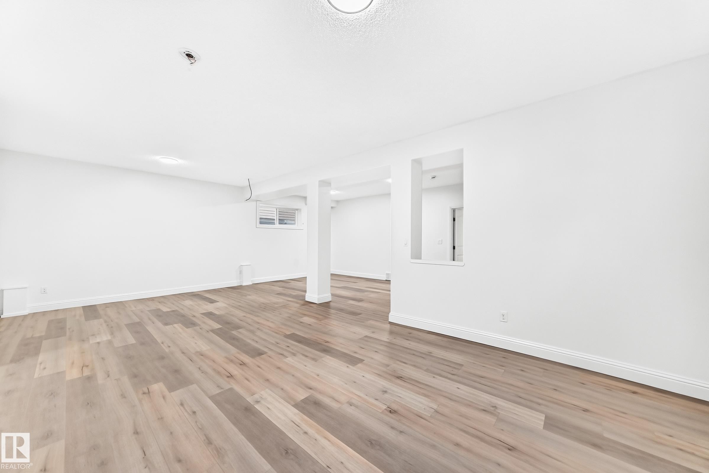 Spacious room featuring wood-finish flooring, white walls, and a recessed window - 1663 Rutherford Road Sw, Edmonton, AB - Indoor Photo Showing Other Room