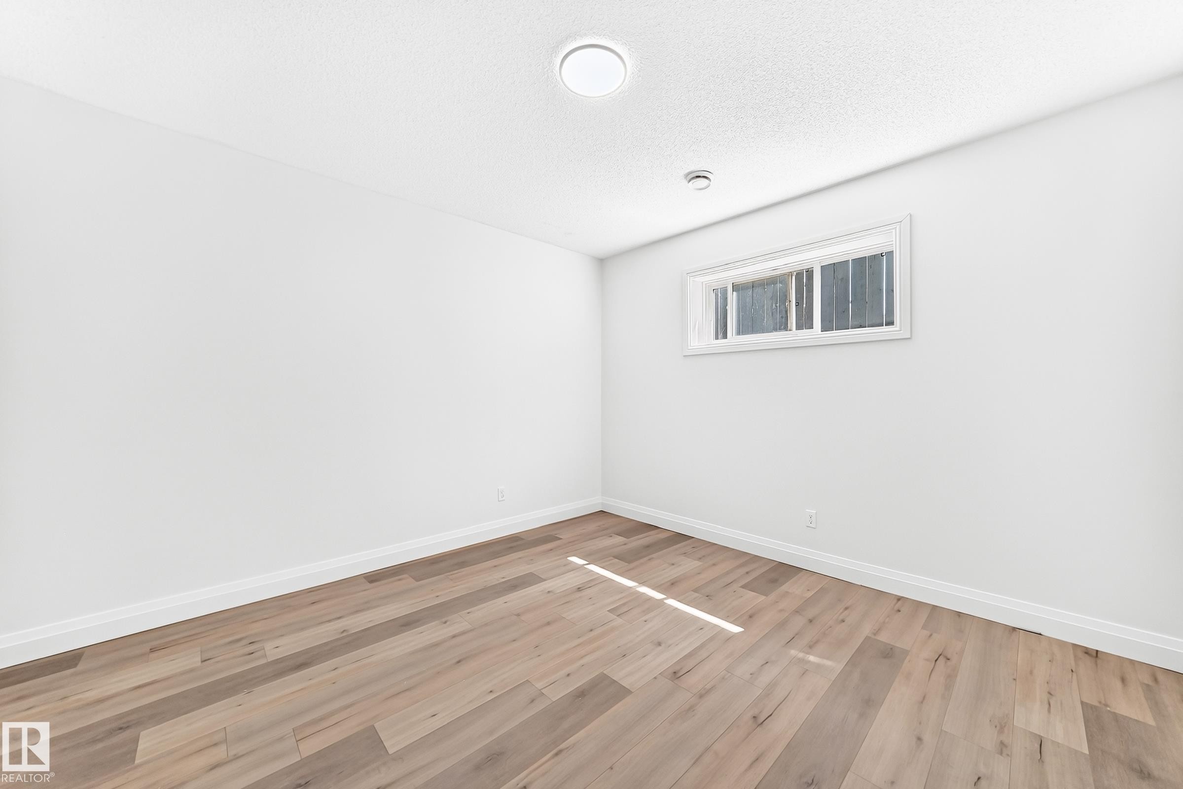 Light wood-finish flooring complements crisp white walls and white trim - 1663 Rutherford Road Sw, Edmonton, AB - Indoor Photo Showing Other Room