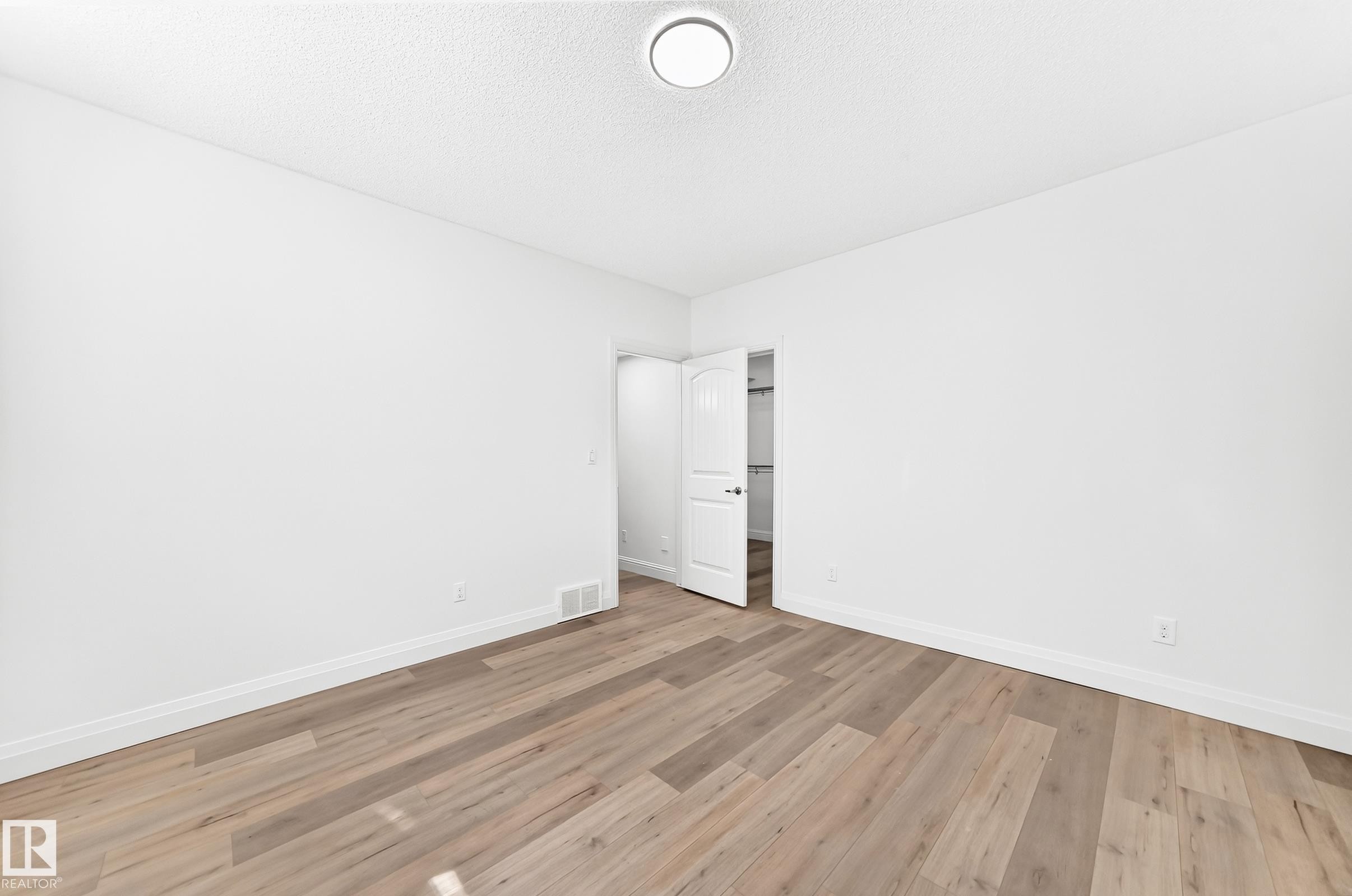 Bright interior room featuring wood-finish flooring, white baseboards, and a neutral wall palette - 1663 Rutherford Road Sw, Edmonton, AB - Indoor Photo Showing Other Room