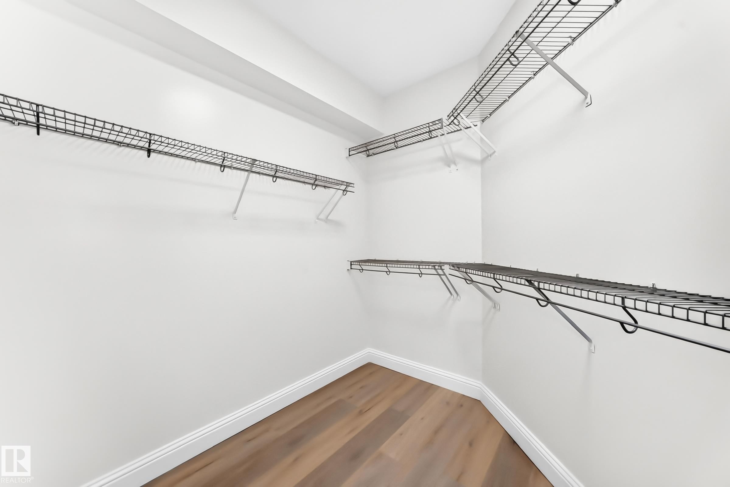 Walk-in closet featuring light wood-finish flooring, white baseboards, and white painted walls - 1663 Rutherford Road Sw, Edmonton, AB - Indoor With Storage
