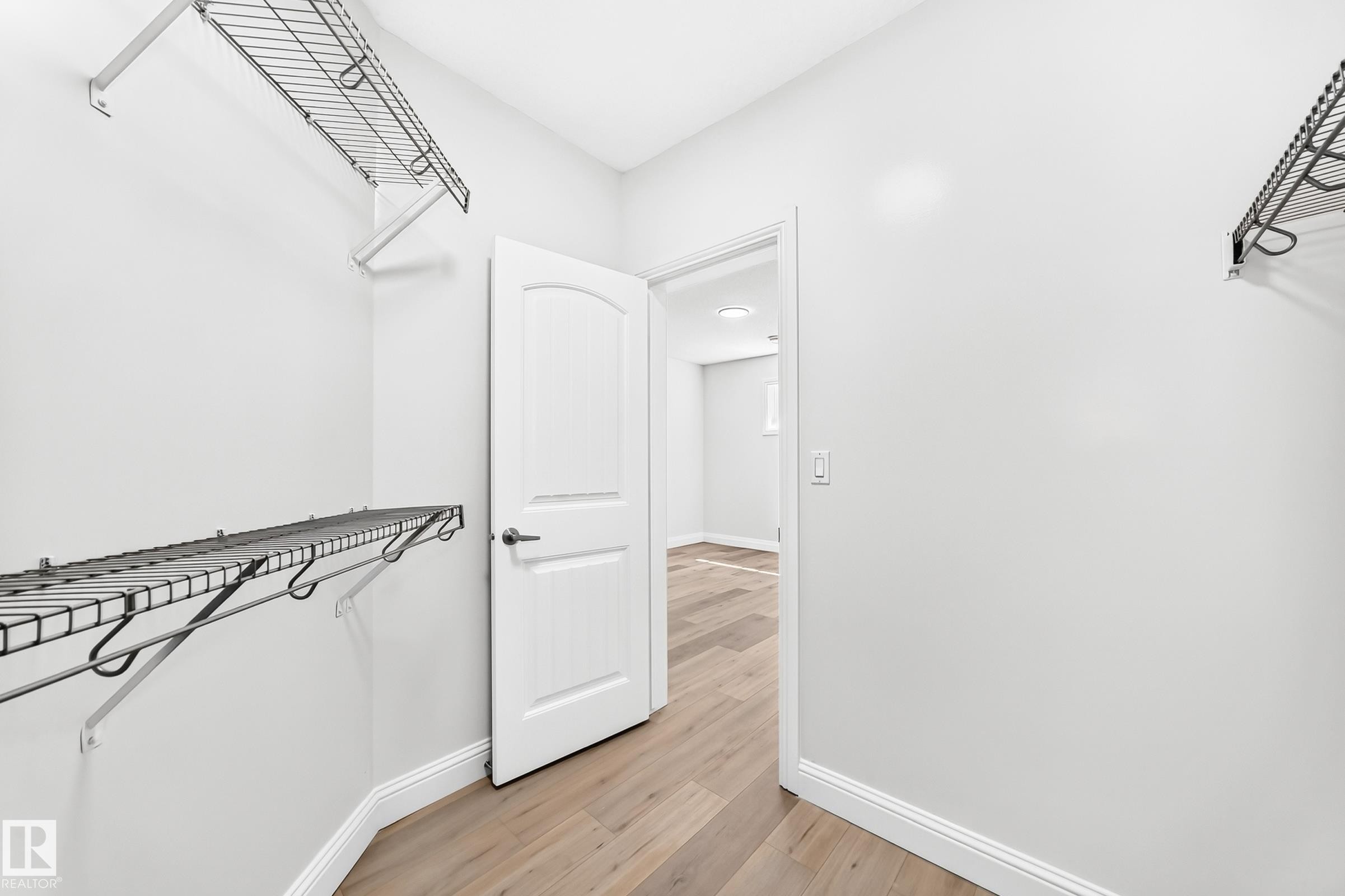 Walk-in closet featuring light wood-finish flooring, white baseboards, and multiple wire shelving units - 1663 Rutherford Road Sw, Edmonton, AB - Indoor