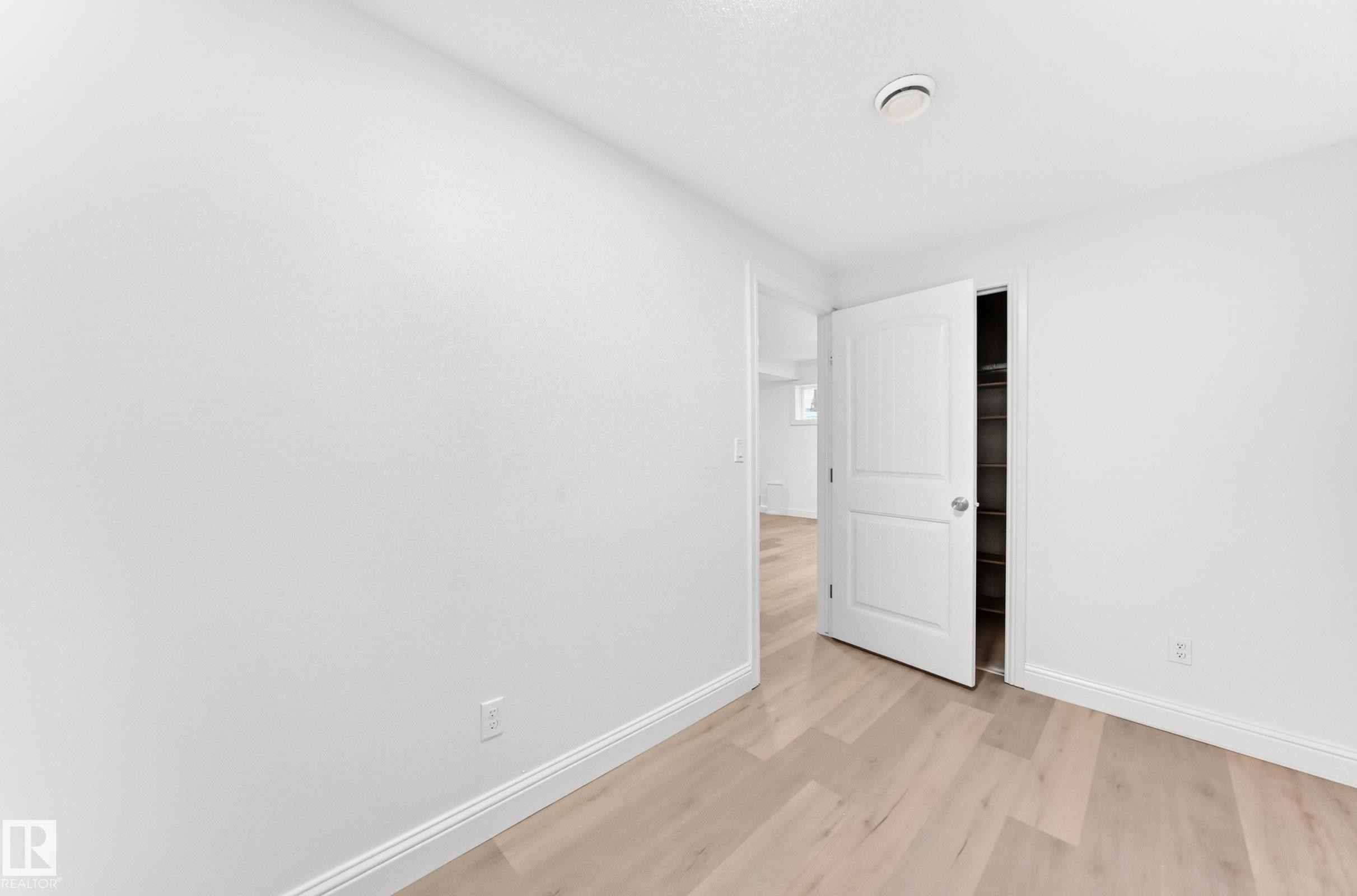Interior room featuring light wood-finish flooring, white walls, and a white paneled door - 1663 Rutherford Road Sw, Edmonton, AB - Indoor Photo Showing Other Room