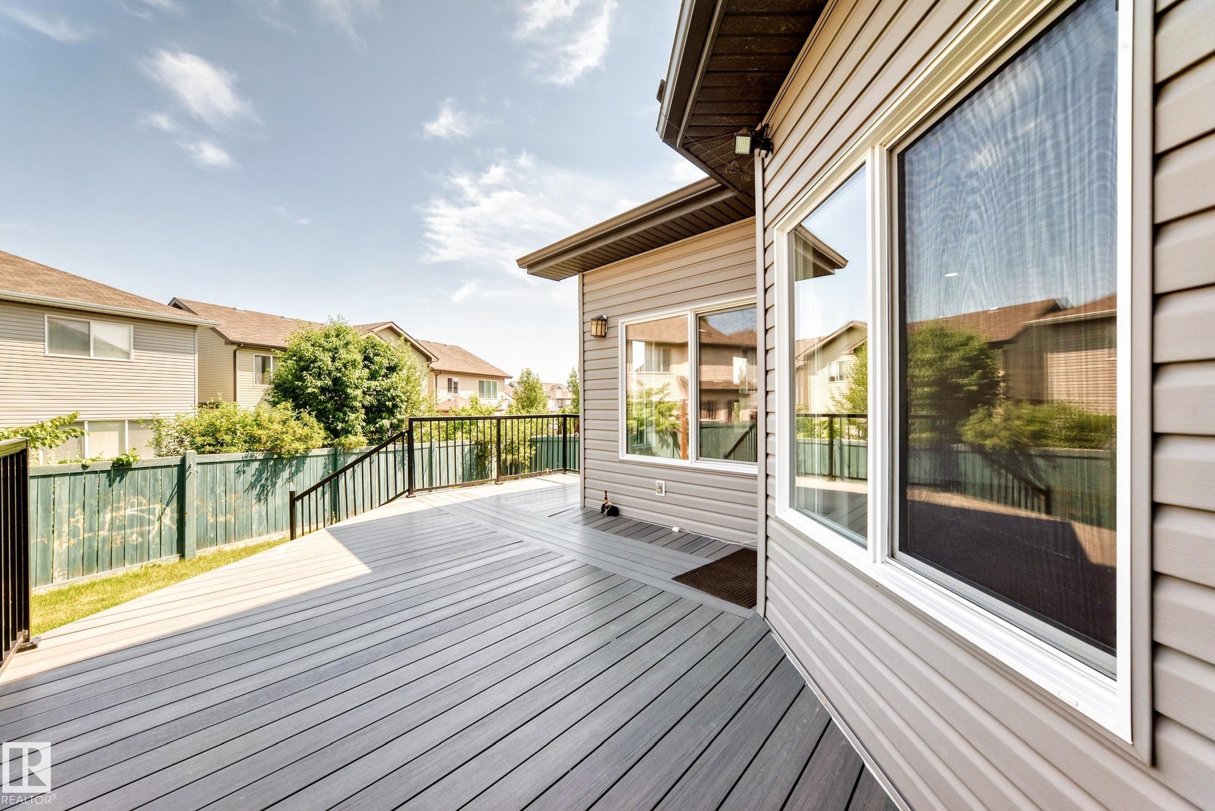 Spacious composite deck with black metal railings, light gray siding, and multiple large windows - 1663 Rutherford Road Sw, Edmonton, AB - Outdoor With Deck Patio Veranda With Exterior