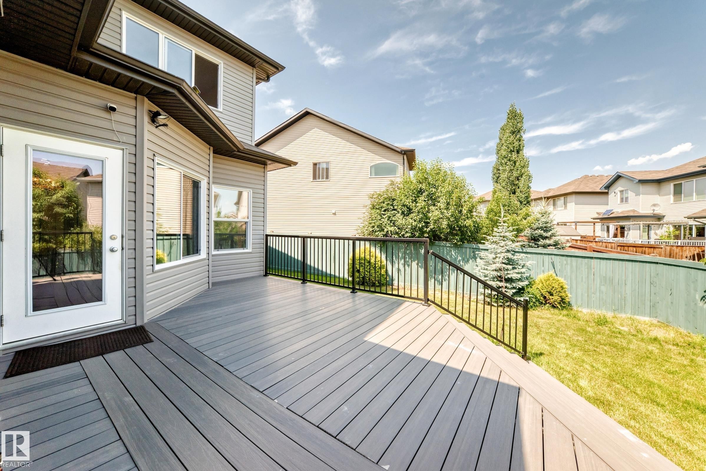 Spacious exterior deck with composite decking, black metal railings, and direct access to the interior via a glass-paneled door - 1663 Rutherford Road Sw, Edmonton, AB - Outdoor With Deck Patio Veranda With Exterior