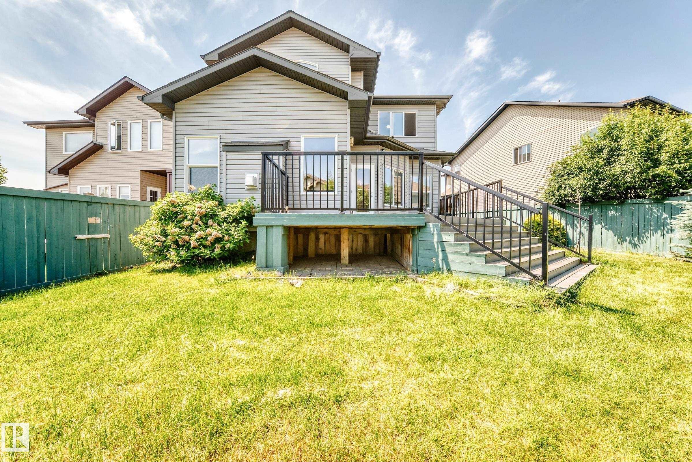 Spacious backyard featuring a multi-level deck with black metal railings, a privacy fence, and a large grassy area - 1663 Rutherford Road Sw, Edmonton, AB - Outdoor With Deck Patio Veranda