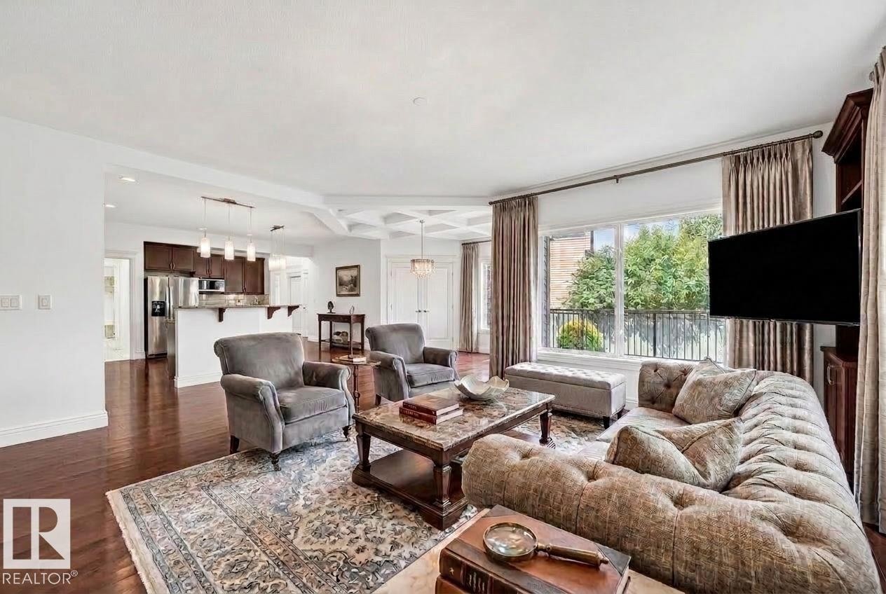 Spacious living area featuring rich wood-finish flooring, a large window with exterior railing, and a coffered ceiling detail - 1663 Rutherford Road Sw, Edmonton, AB - Indoor Photo Showing Living Room