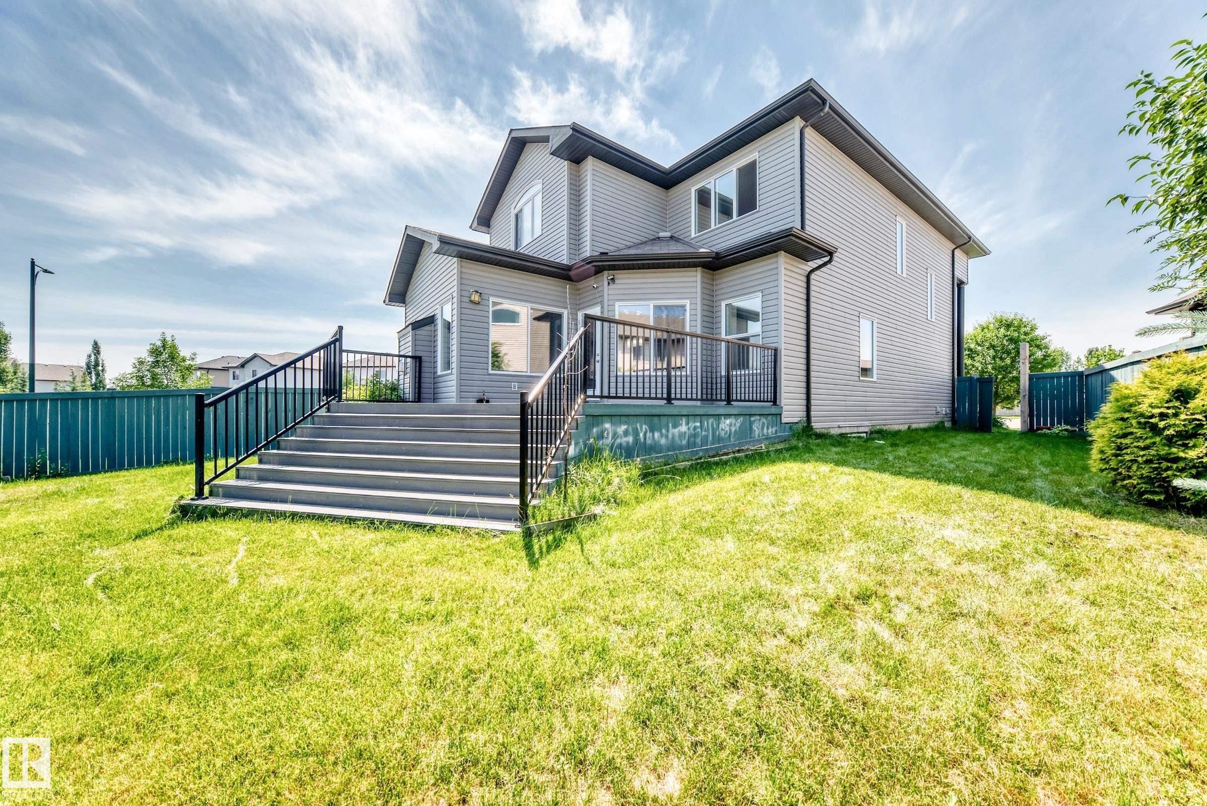 Spacious backyard featuring a multi-level deck with dark railings and steps, light gray siding, and a dark shingle roof - 1663 Rutherford Road Sw, Edmonton, AB - Outdoor With Deck Patio Veranda