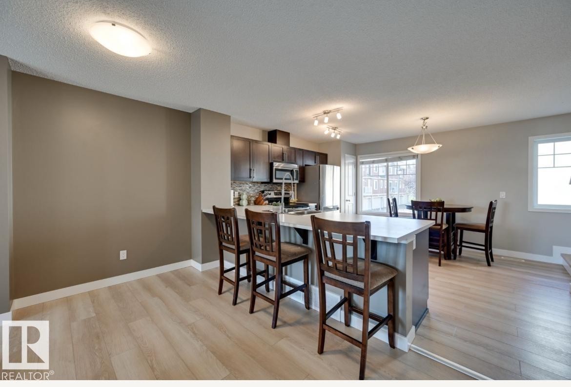 Open-concept kitchen and dining area with wood-finish flooring - #16 460 Hemingway Rd Nw, Edmonton, AB - Indoor Photo Showing Dining Room