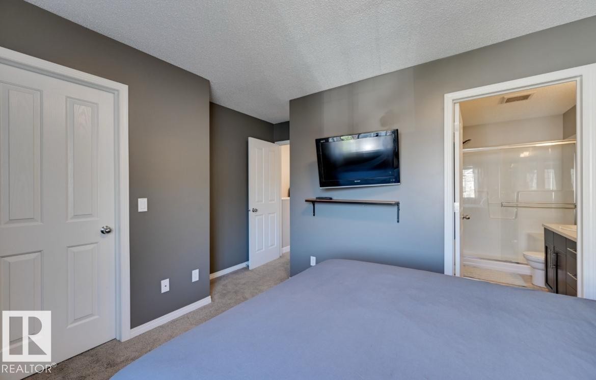 Bedroom with neutral gray wall paint, textured ceiling, and carpet flooring - #16 460 Hemingway Rd Nw, Edmonton, AB - Indoor Photo Showing Bedroom