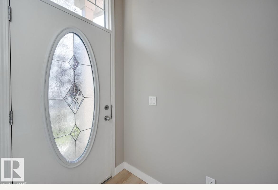 Entry door with an oval leaded glass insert, transom window, and brushed nickel hardware - #16 460 Hemingway Rd Nw, Edmonton, AB - Indoor Photo Showing Other Room